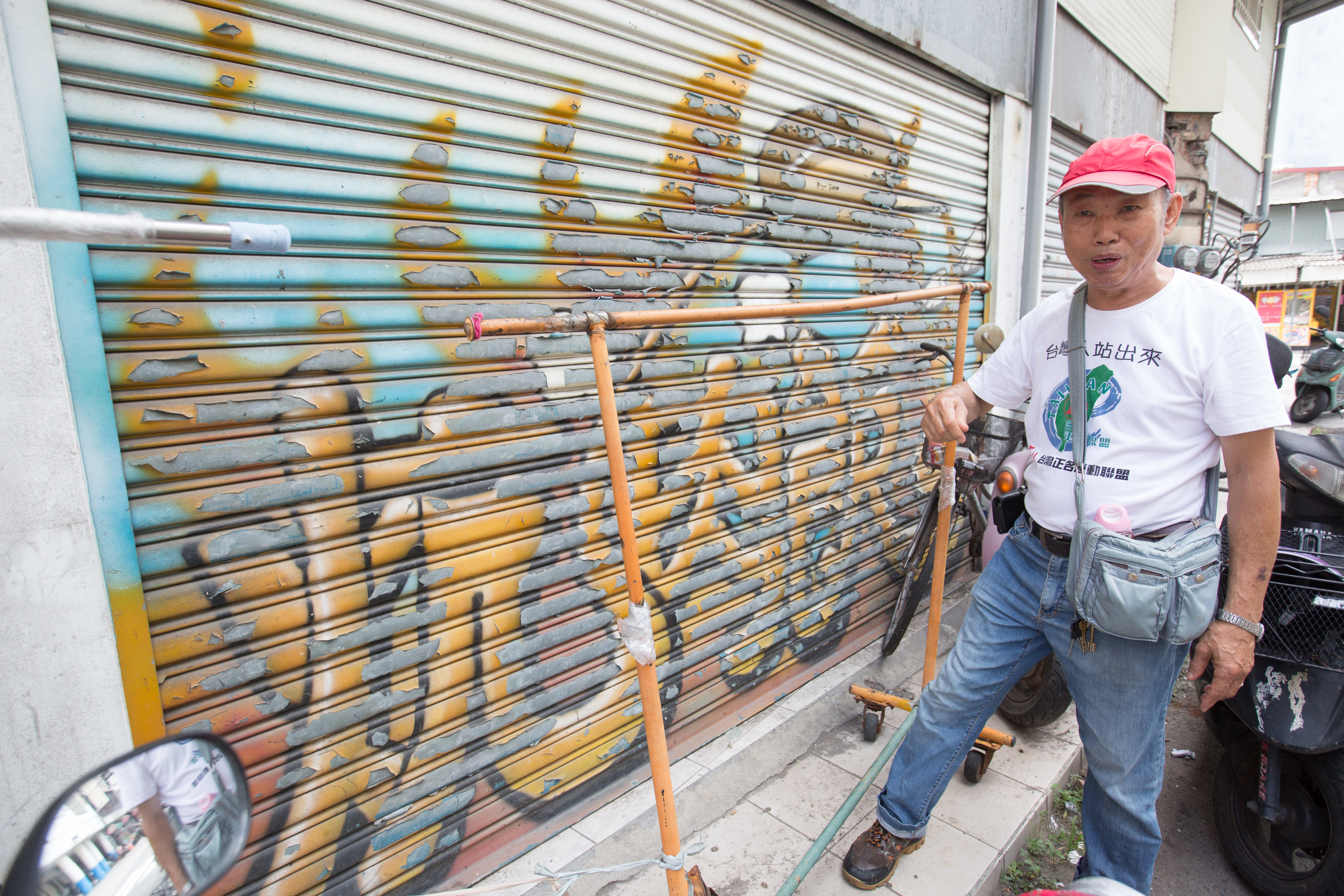 鄧永成回到舊店面，昔日的噴漆塗鴉已斑駁。