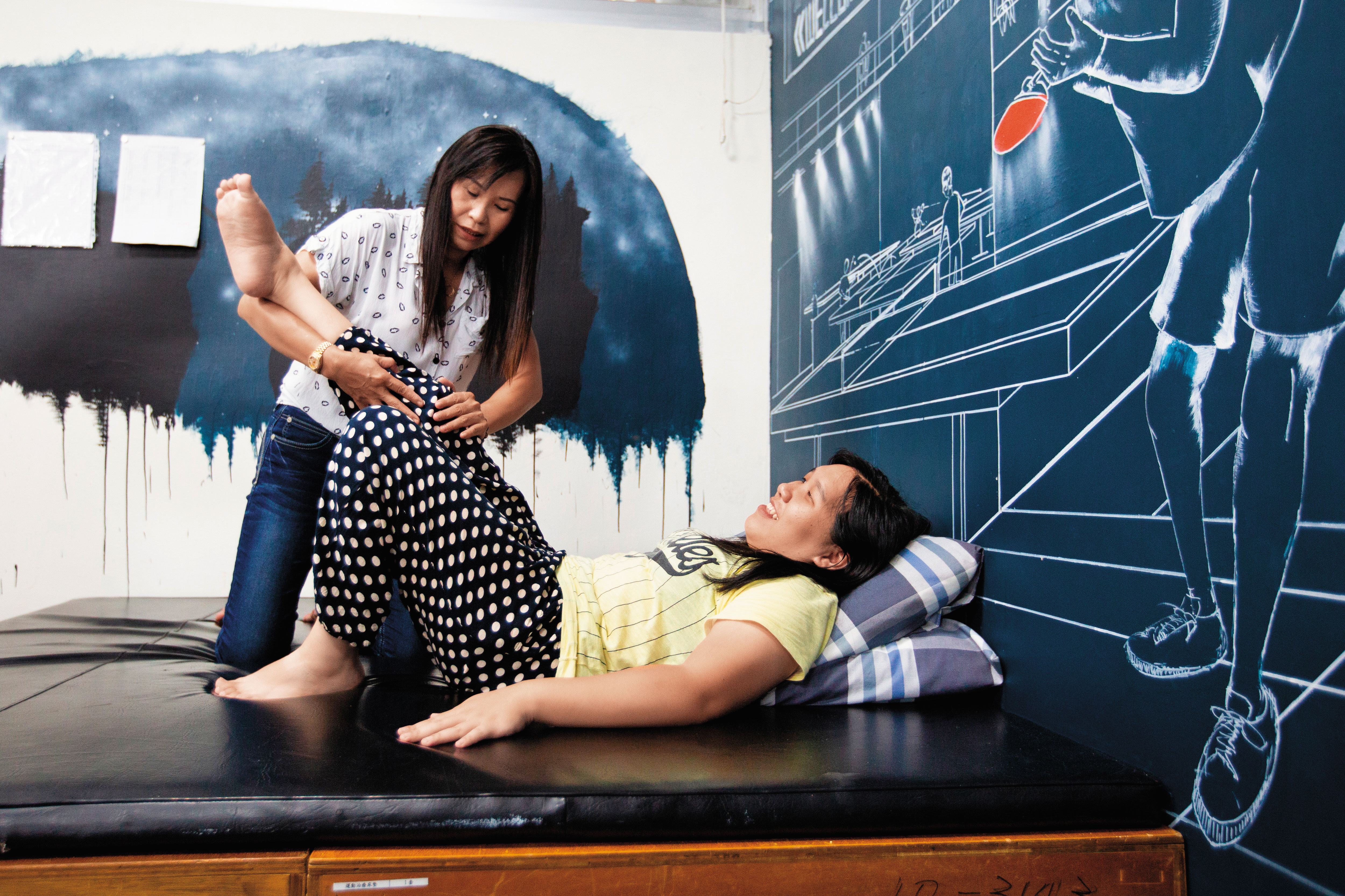 長明慧（右）的身體右半邊癱瘓，右腳扭曲變形，肌肉張力強，需常按摩復健。