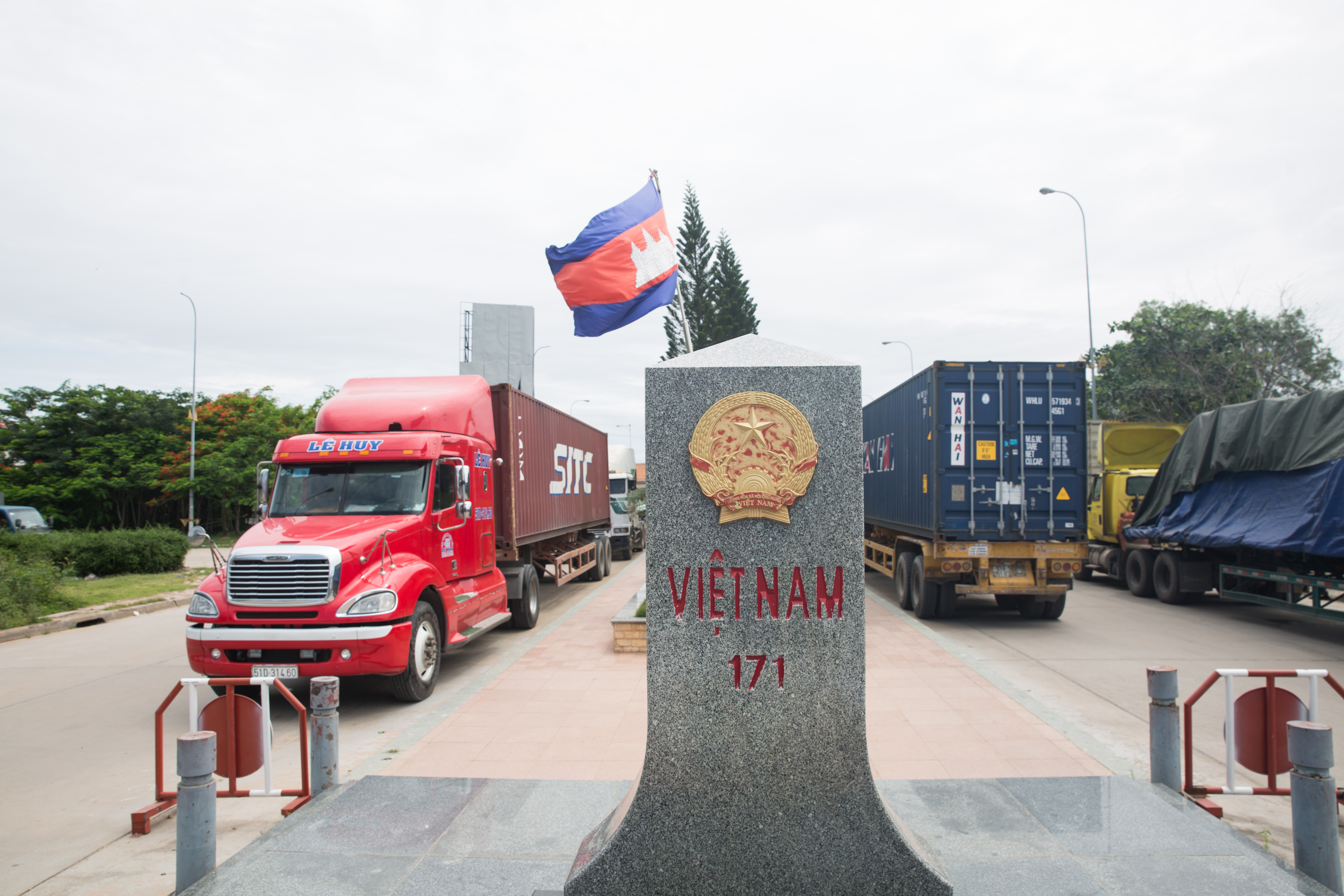 在柬埔寨與越南邊境處，百輛貨櫃車頂著超過35度高溫，排起長長車陣、準備通關。