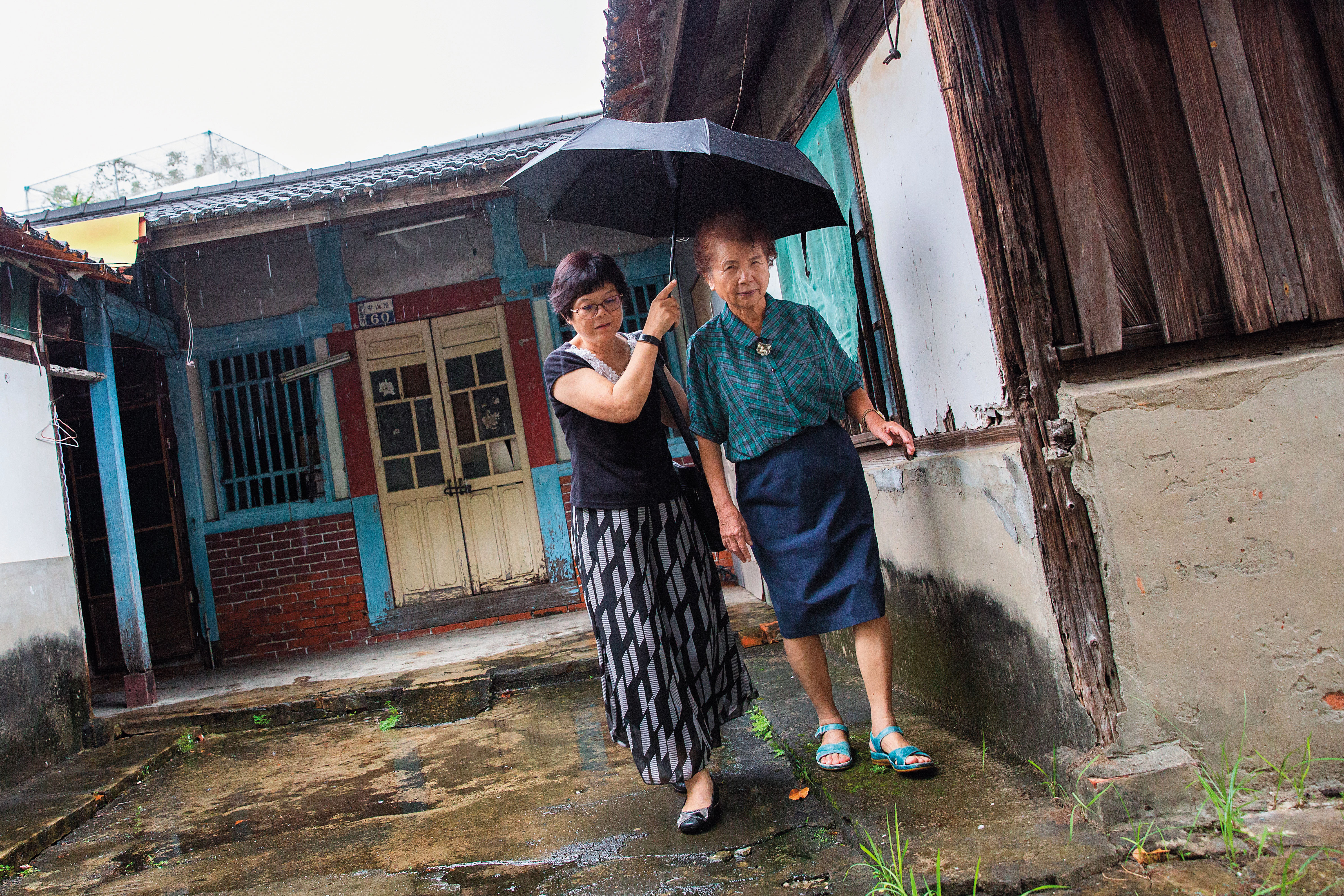 陳楊麗蓉（右）帶我們來到附近老家，牆壁下半部是磚頭所砌，當時只有少數人家能負擔這種花費，與窗戶同高的白牆則是以竹片和水泥糊成，上方屋瓦也是自家工廠製作。