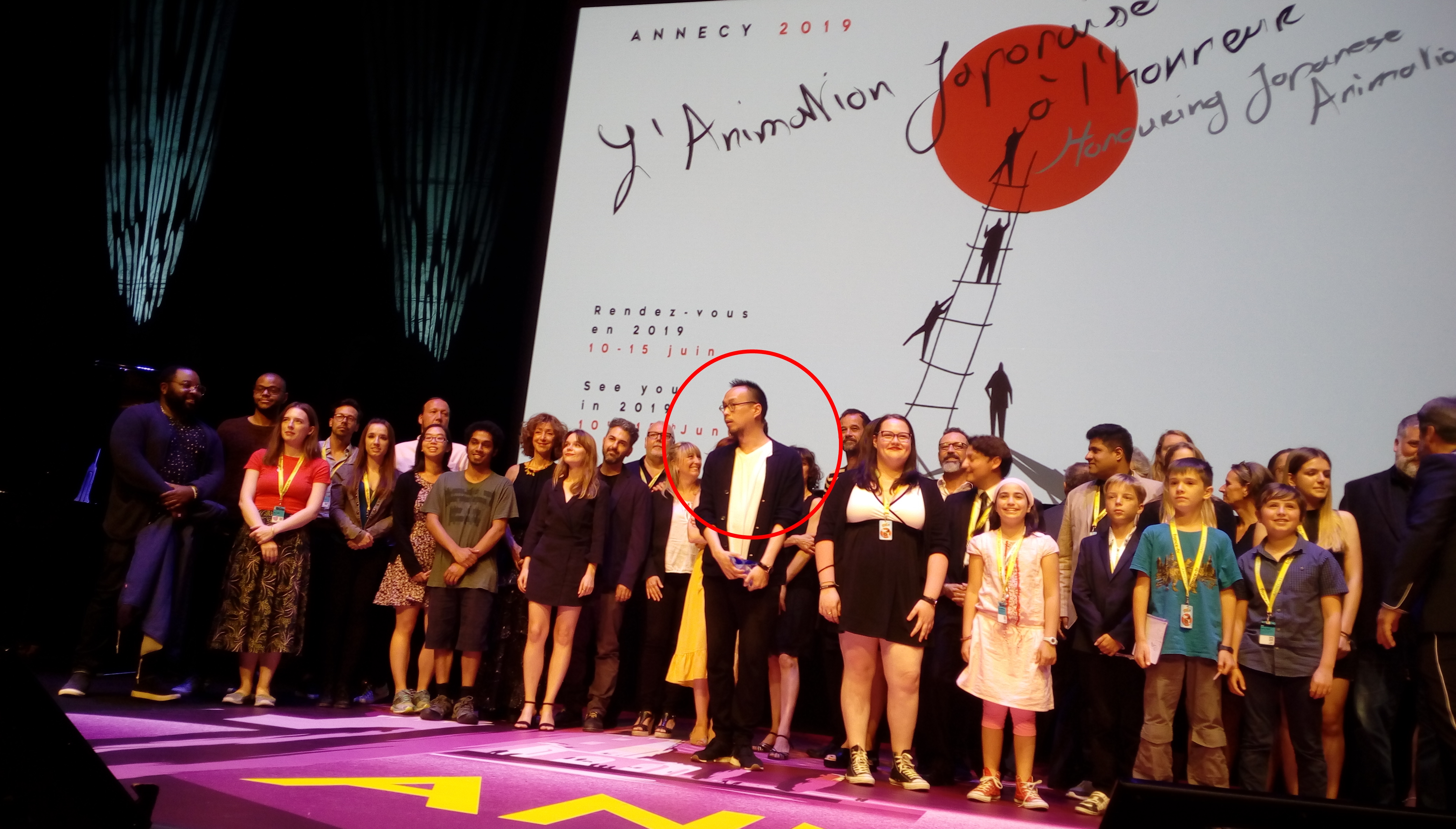 杜來順（紅圈處）是今年安錫影展的風雲人物。背景是明年主題國日本的廣告。（BAC Films提供）