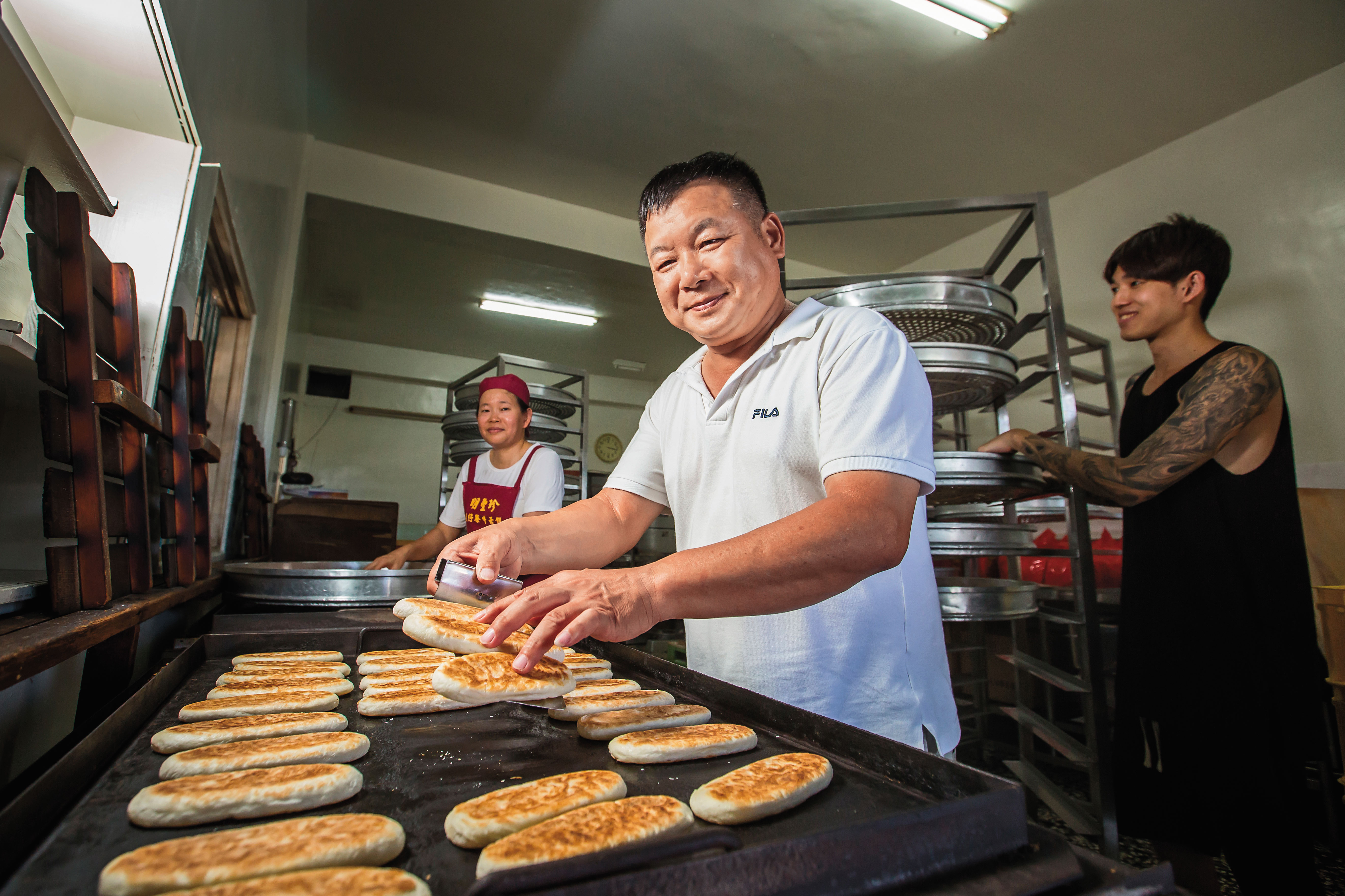 蘇正興（中）29年前偕妻子黃美珠（左），臨危接下明豐珍兔仔寮牛舌餅家業，長子蘇志偉（右）從小就要幫忙做餅。
