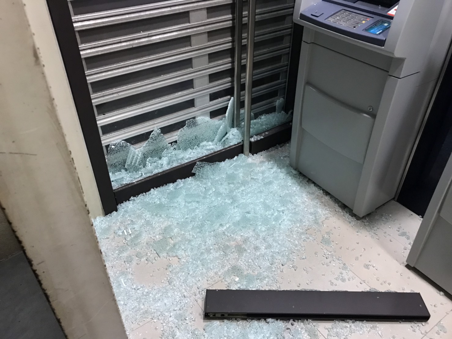 李姓男子指稱存款遭侵吞，持榔頭砸毀銀行玻璃門，現場碎裂一地。（翻攝畫面）