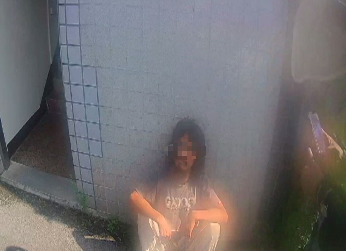 披頭散髮的林男子躺在騎樓大睡，竟被警方查獲通緝犯的身分。（翻攝畫面）