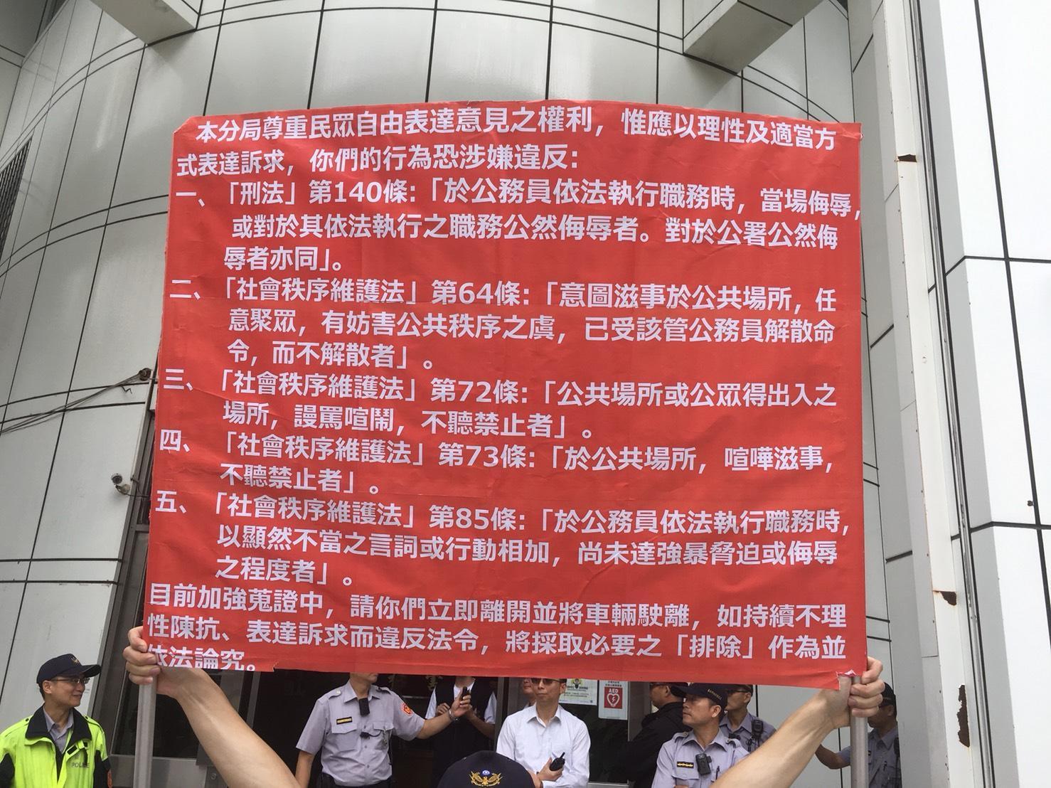 盧朝財等人聚眾抗議,警方舉牌告知違法。(翻攝畫面)