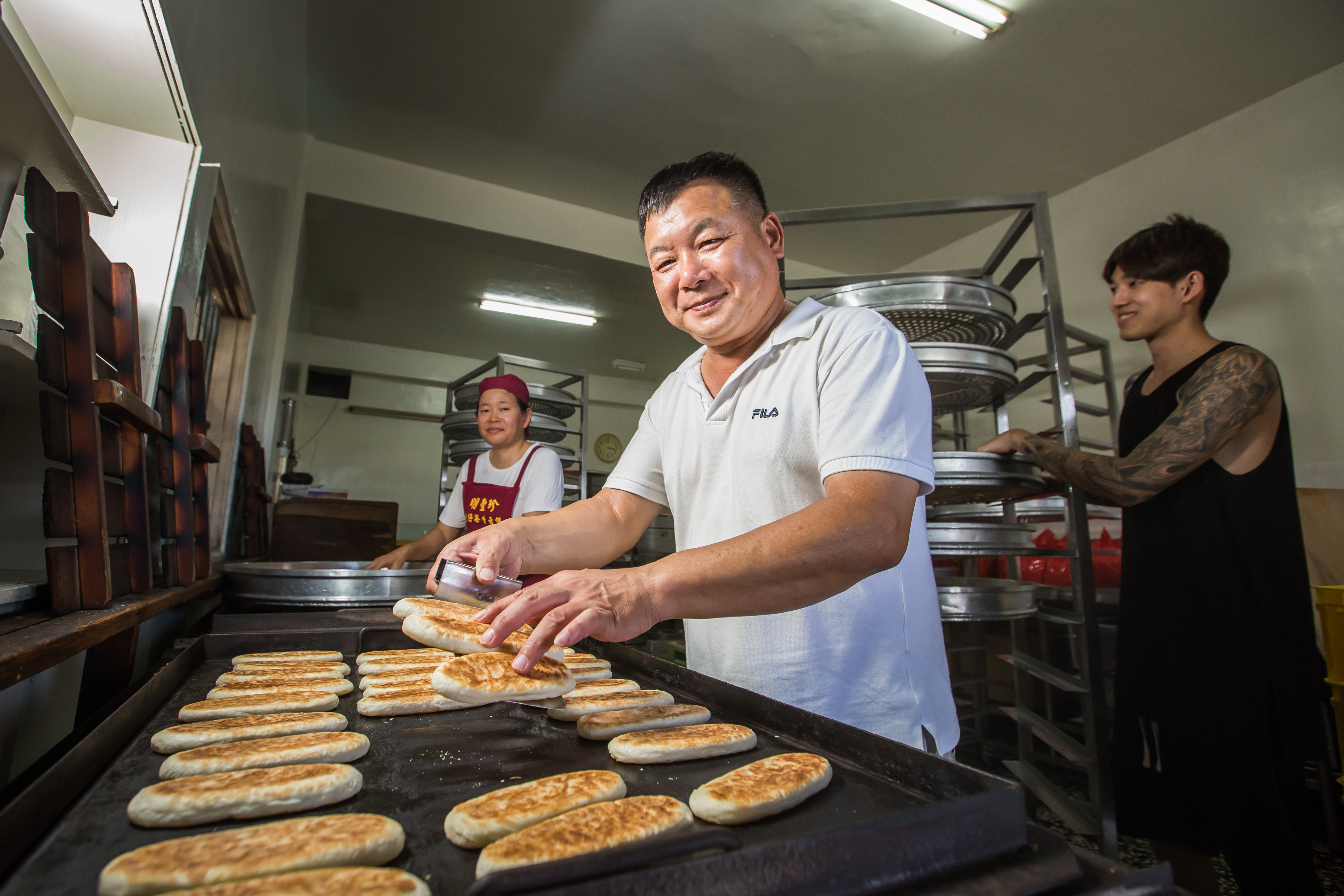 蘇正興（中）29年前偕妻子黃美珠（左），臨危接下明豐珍兔仔寮牛舌餅家業，長子蘇志偉（左）從小就要幫忙做餅。