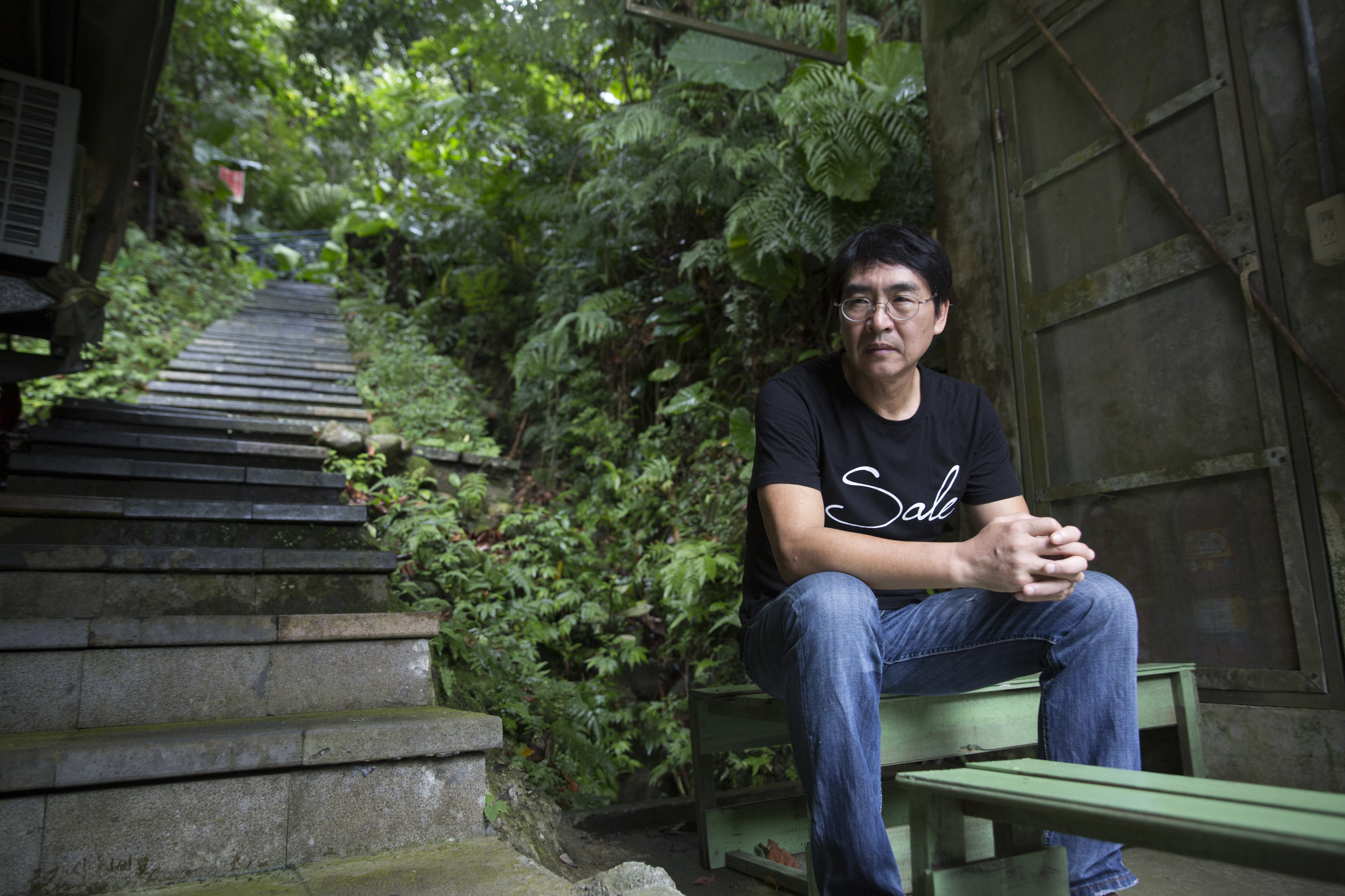 董振良坐在新店租處外的登山小徑，他說這裡很像他的家鄉金門。