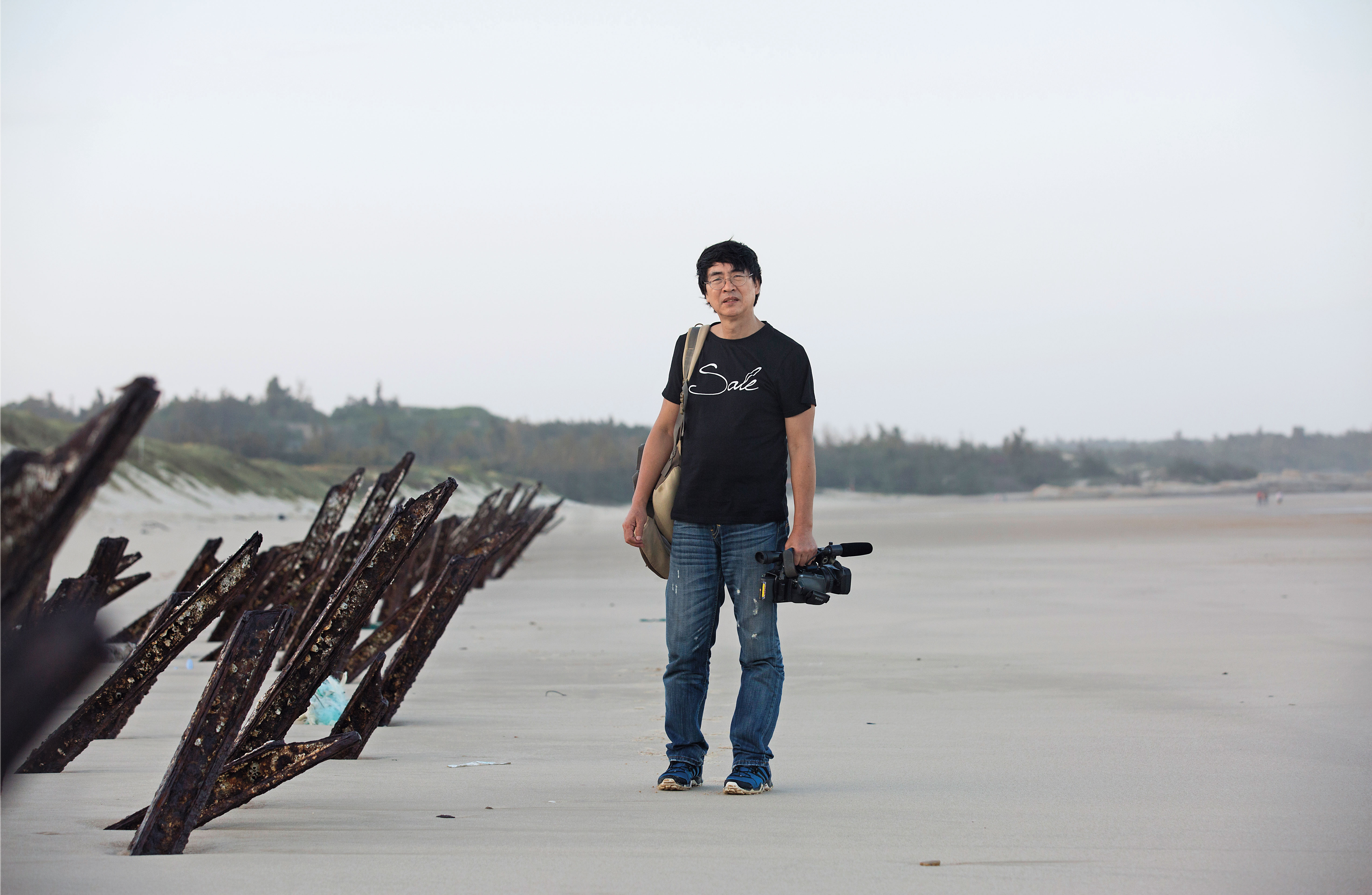 董振良手上的攝影機，陪伴他度過十餘寒暑，他獨自佇立在金門蒼茫的沙灘上，正如他孤寂的心境一般。