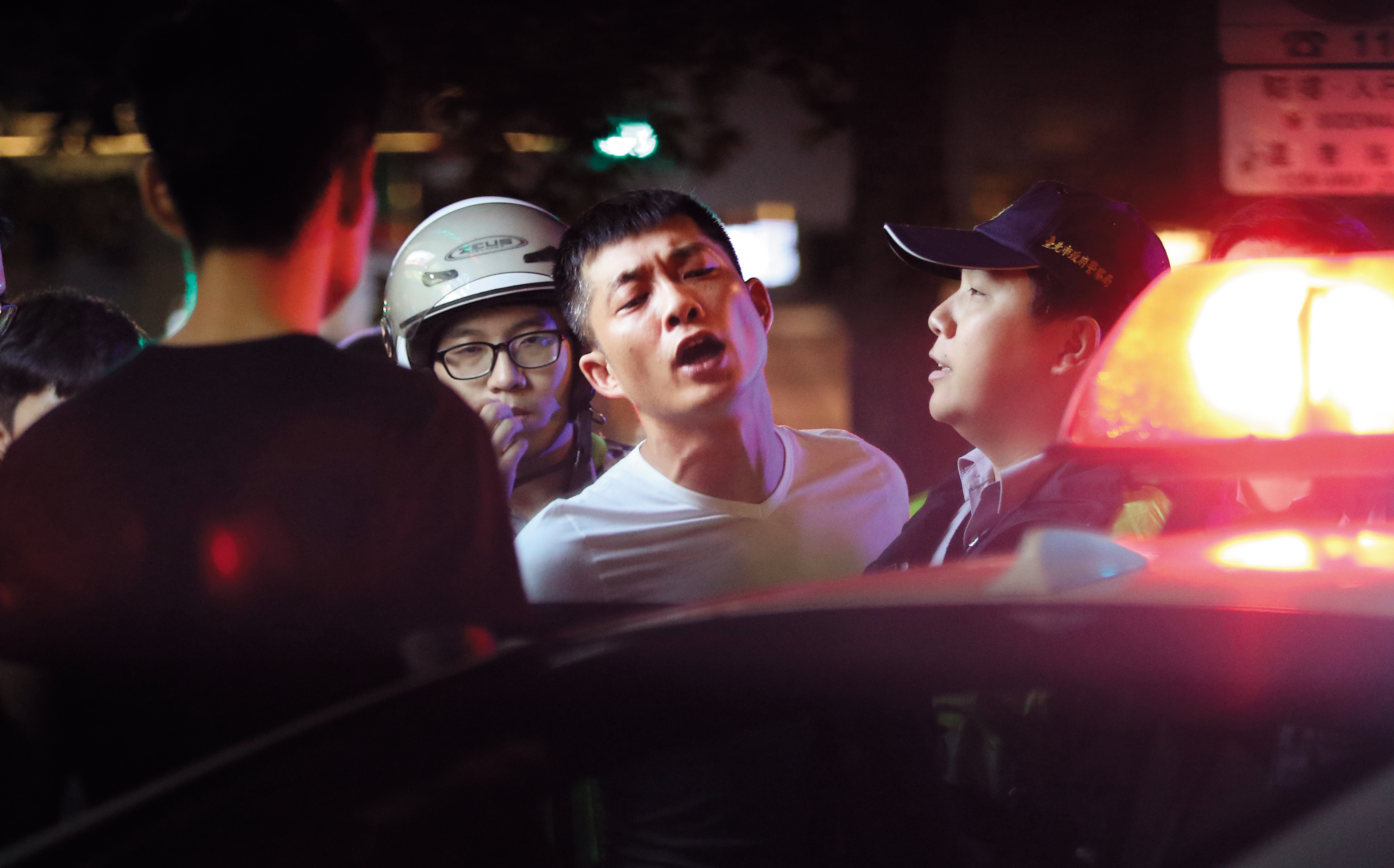 10月9日 04：42 白衣男子也是衝突中心，他被押上警車時，表情依舊激動。