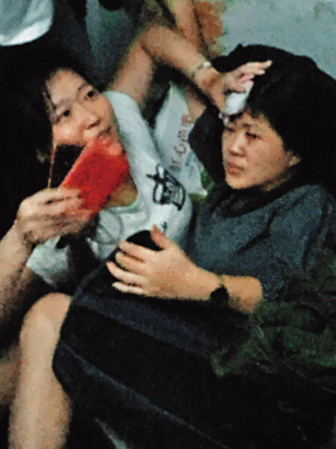 列車出軌後，輕傷的戴太太在車廂內以手按壓受傷者頭部，等待救援。（戴先生提供）