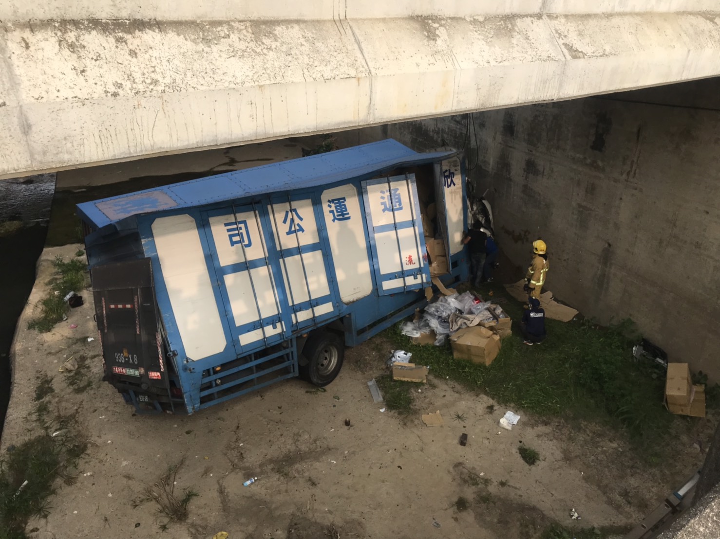 物流公司貨運車翻落約2至3層樓深的大排下，車頭嚴重凹陷變形，車體也扭曲，貨物散落一地。（警方提供）