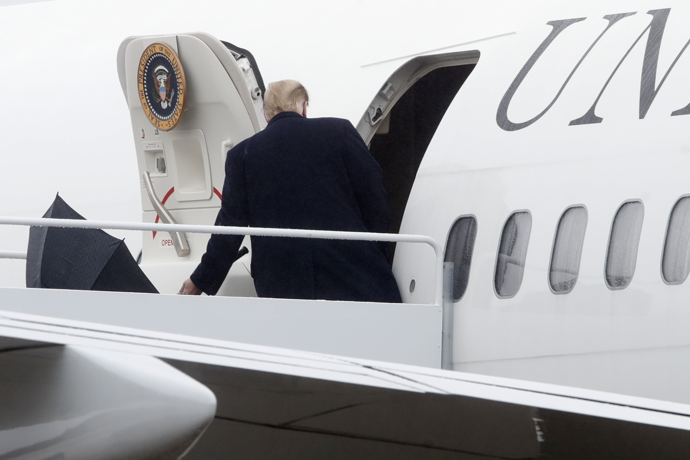 川普雨中撐傘登機，索性把傘一丟。（東方IC）