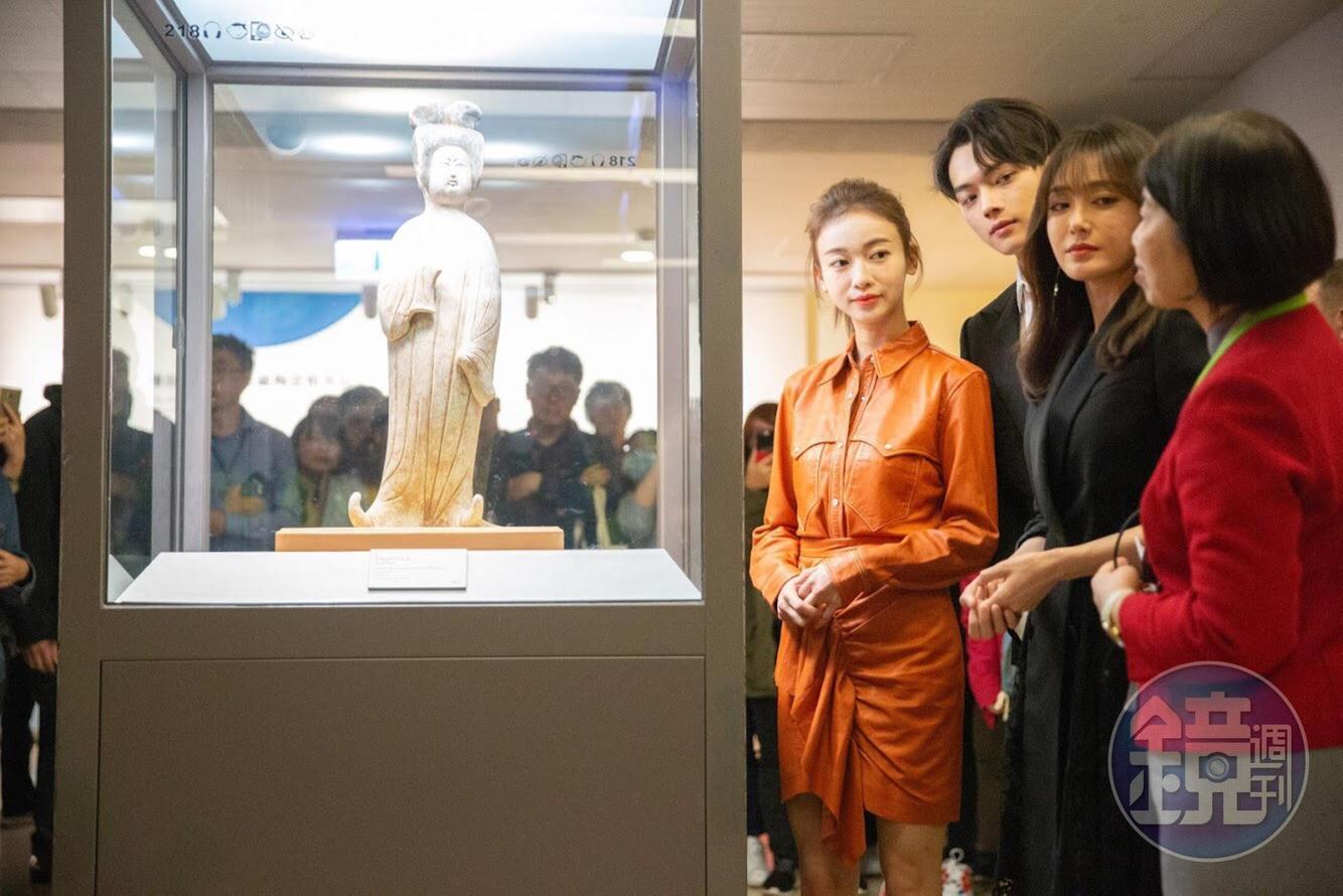 三人專心觀看唐代灰陶加彩仕女俑並聽導覽人員解說。