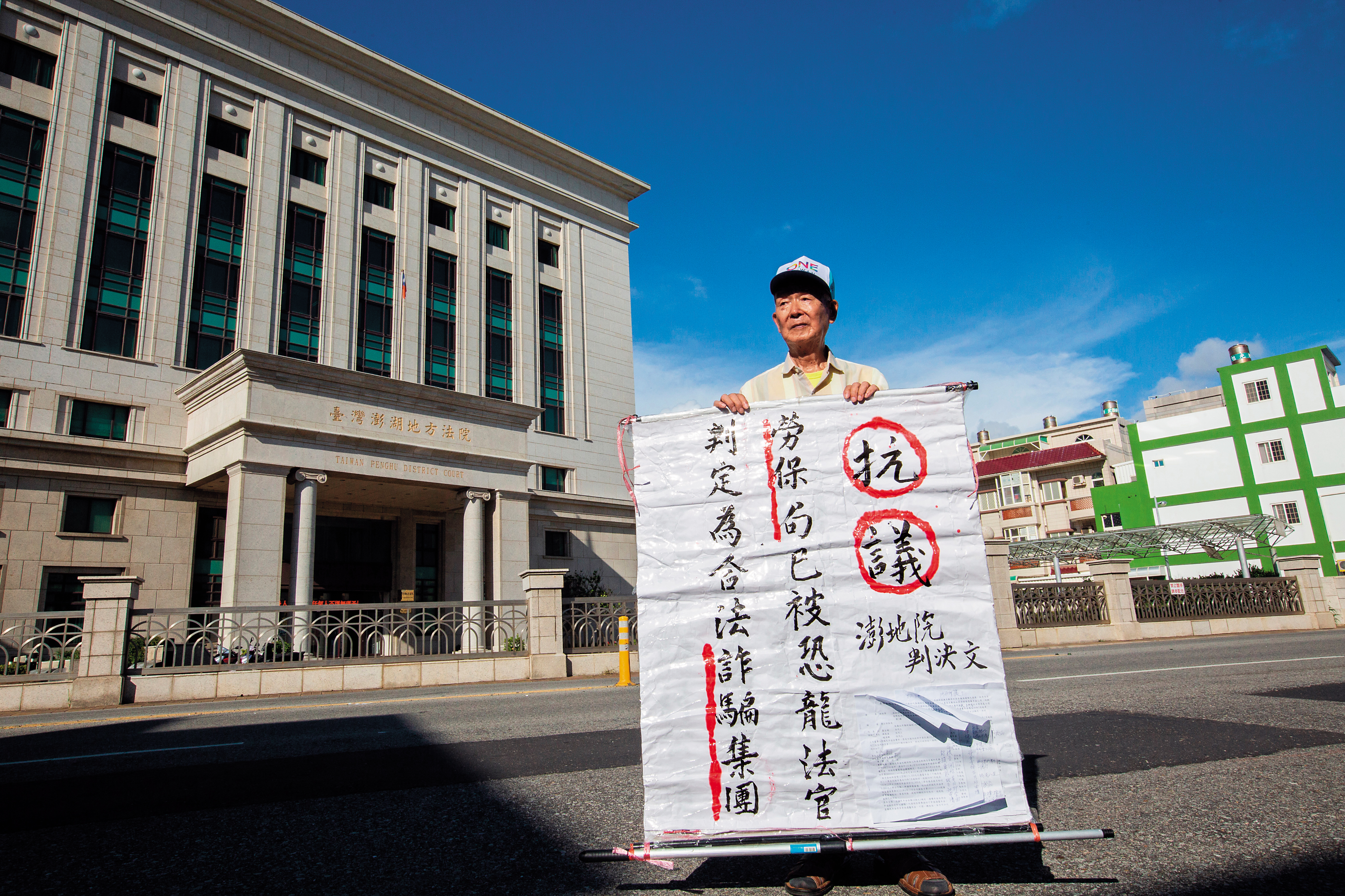先前林挺泰總是拿著這樣的大字報，一個人站在法院前抗議。