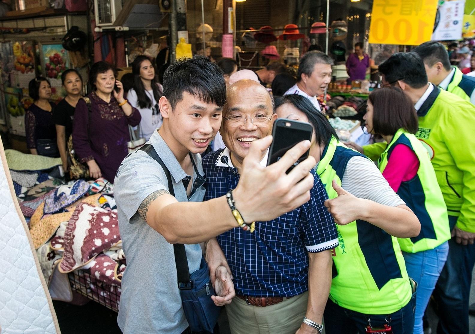 民進黨新北市長候選人蘇貞昌今到板橋區市場掃街拜票,熱情民眾與他自拍留念。(蘇貞昌辦公室提供)