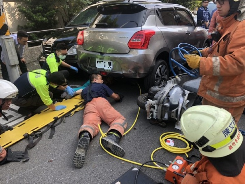消防人員鑽到車底搶救老婦。（警方提供）