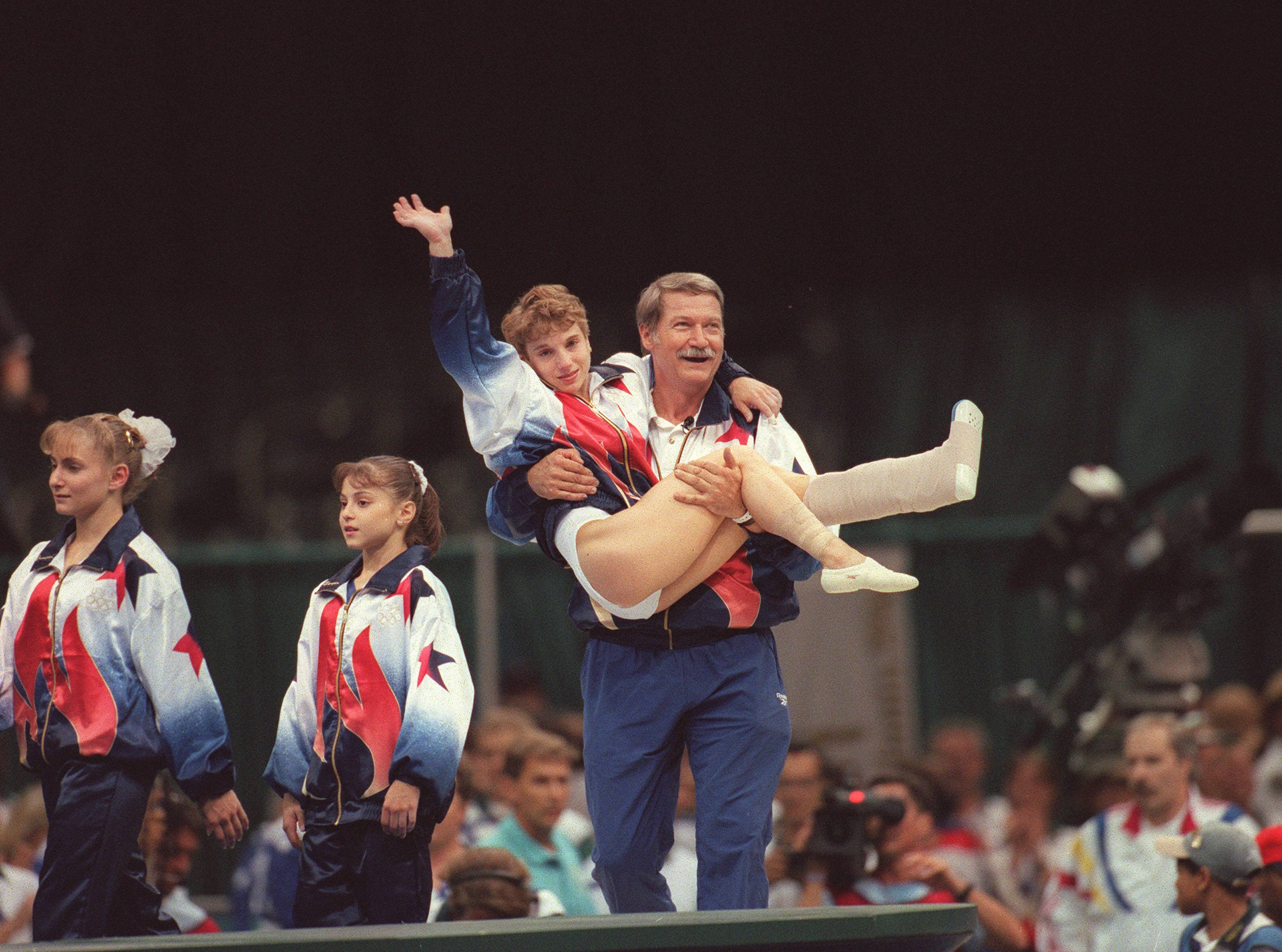 Kerri Strug在96年奧運會上帶傷完成比賽後，被教練抬起，揮手向觀眾致意。（東方IC）