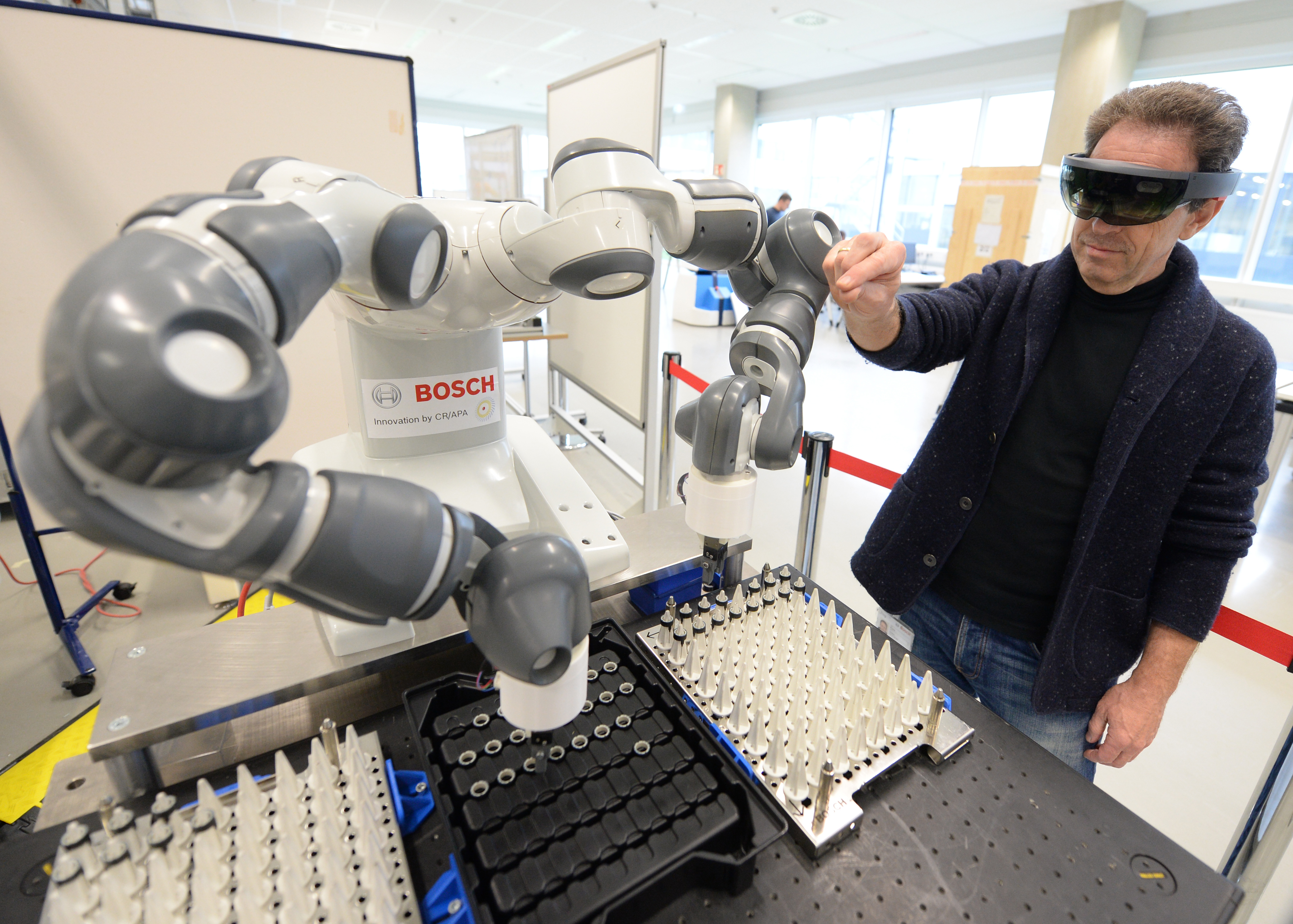 德國實驗室人員戴著全像眼鏡操作機械手臂。（東方IC）