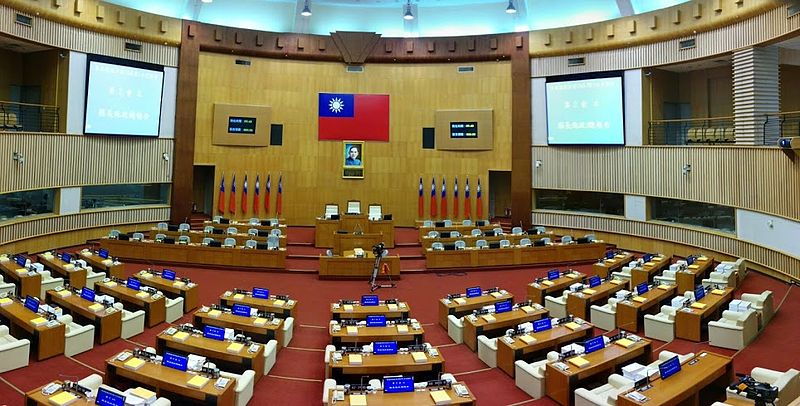 屏東縣因爆發議長賄選案，8位縣議員入獄，依規定遞補5名議員。圖為屏東縣議會議場。（維基百科）