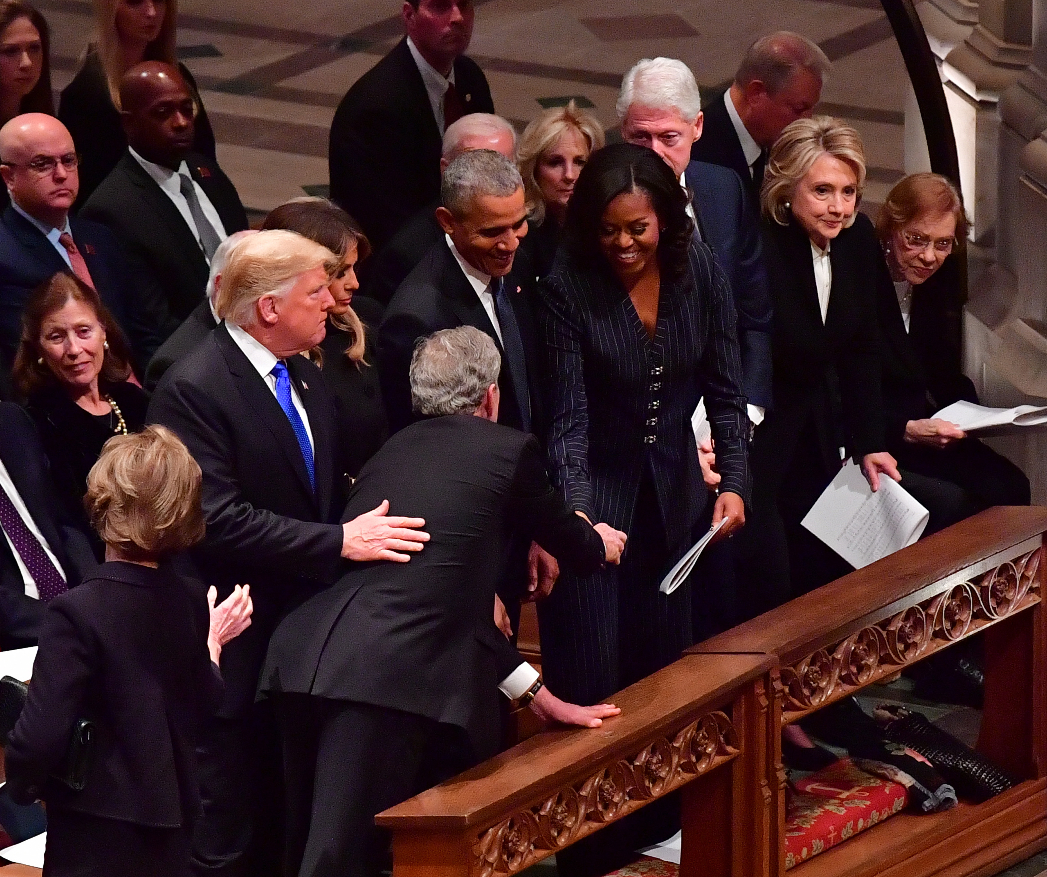 小布希與川普打招呼後，拿出糖果給前第一夫人蜜雪兒．歐巴馬的舉動，引發討論。（東方IC）
