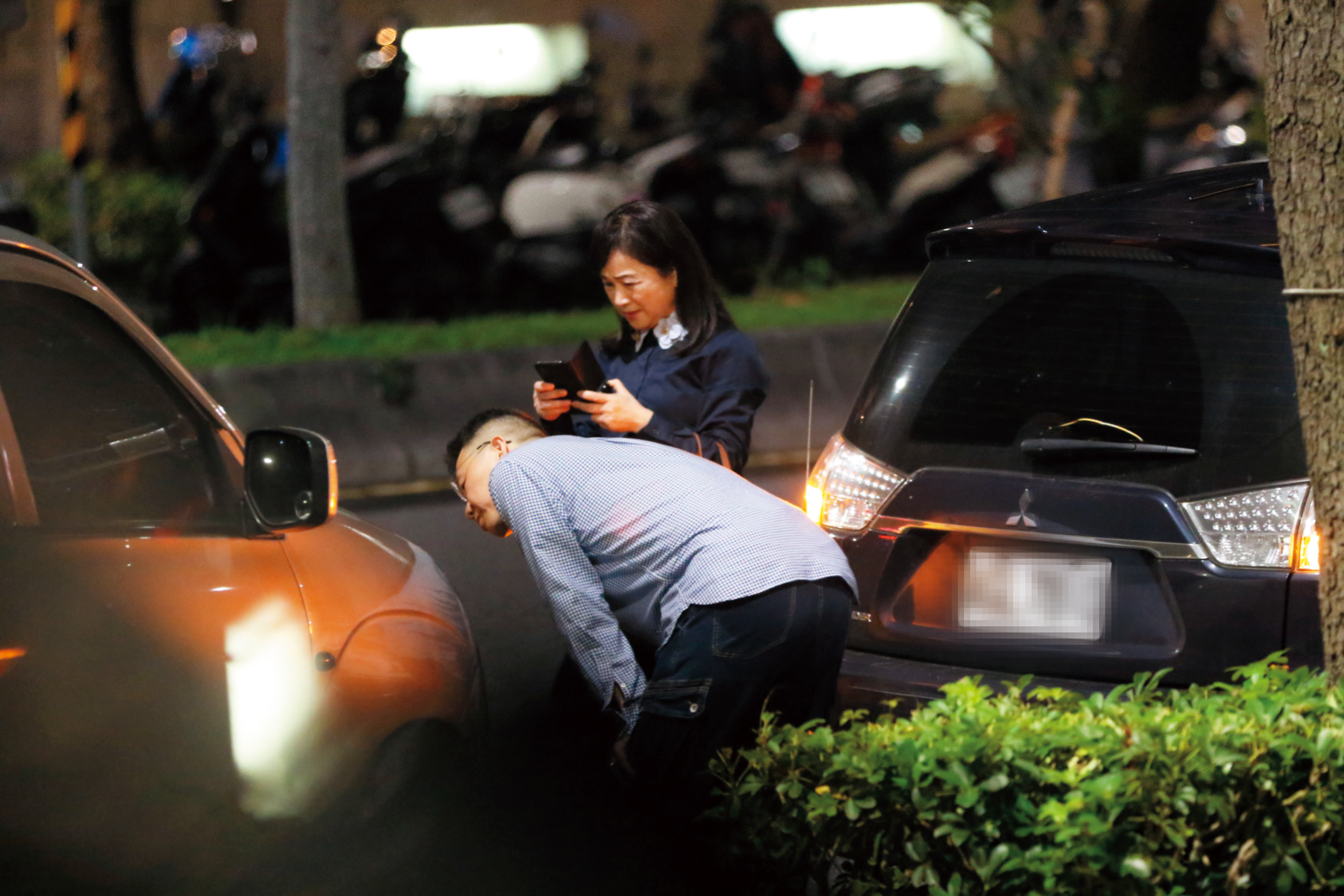 18:40被周玉蔻(右)開車撞到車頭的車主,彎下腰觀看車子損害狀況,周玉蔻在一旁表情尷尬。