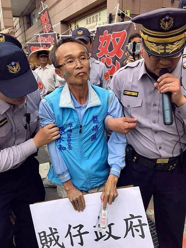 今年3月14日,反龍崎掩埋場自救會北上抗議,陳永和(中)臉上塗著故鄉土地的泥岩,因違法集會被警察架離。(翻攝陳永和臉書)