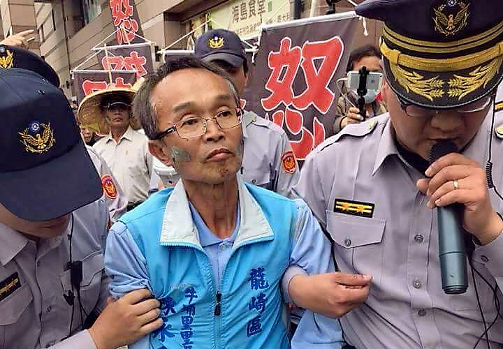 今年3月14日，反龍崎掩埋場自救會北上抗議，陳永和（中）臉上塗著故鄉土地的泥岩，因違法集會被警察架離。（翻攝陳永和臉書）