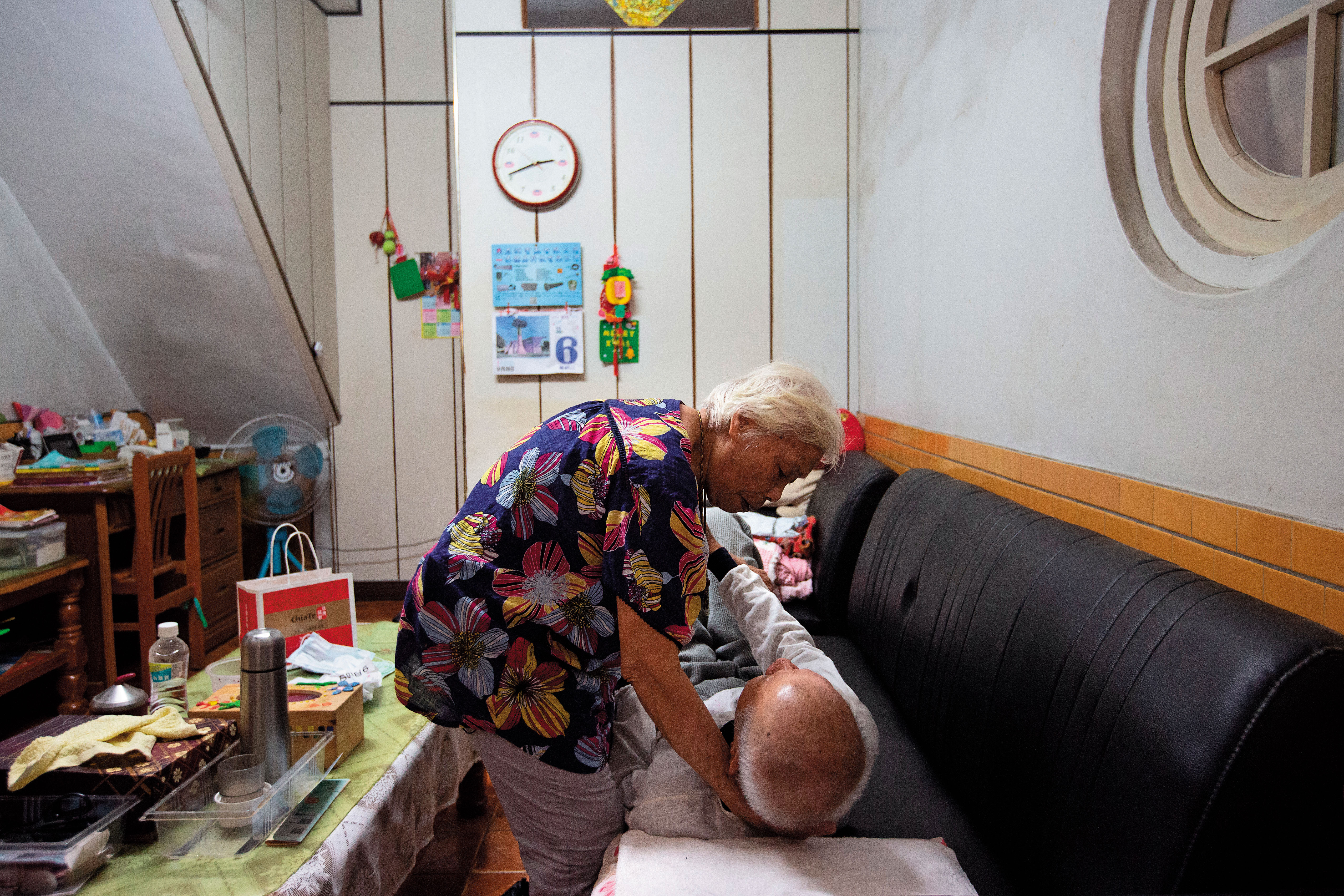 因家中臥房設計不便出入，吳連珠（站立者）和翁興雄（躺臥者）平日以沙發為床，兒子也因此將沙發墊高，方便2人起身。