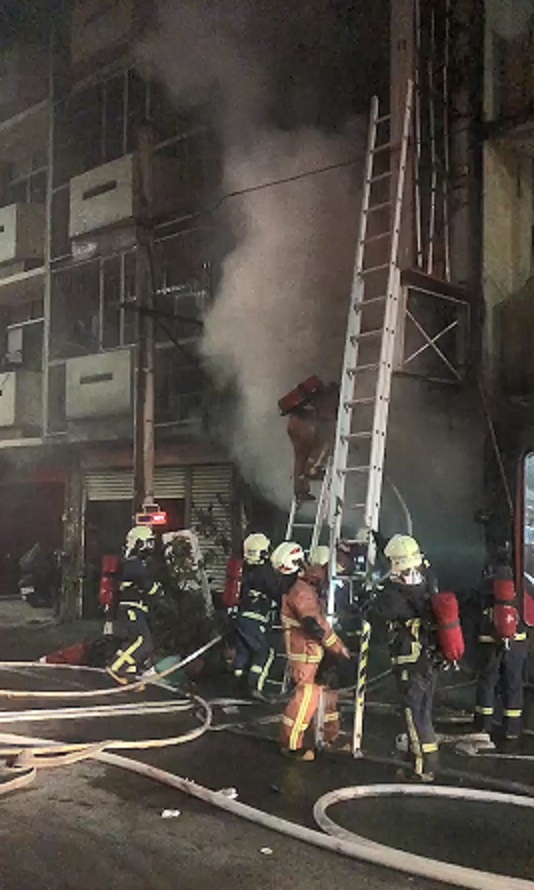 火勢延燒二、三樓，稍降溫後消防人員爬梯進入搜救。（警方提供）