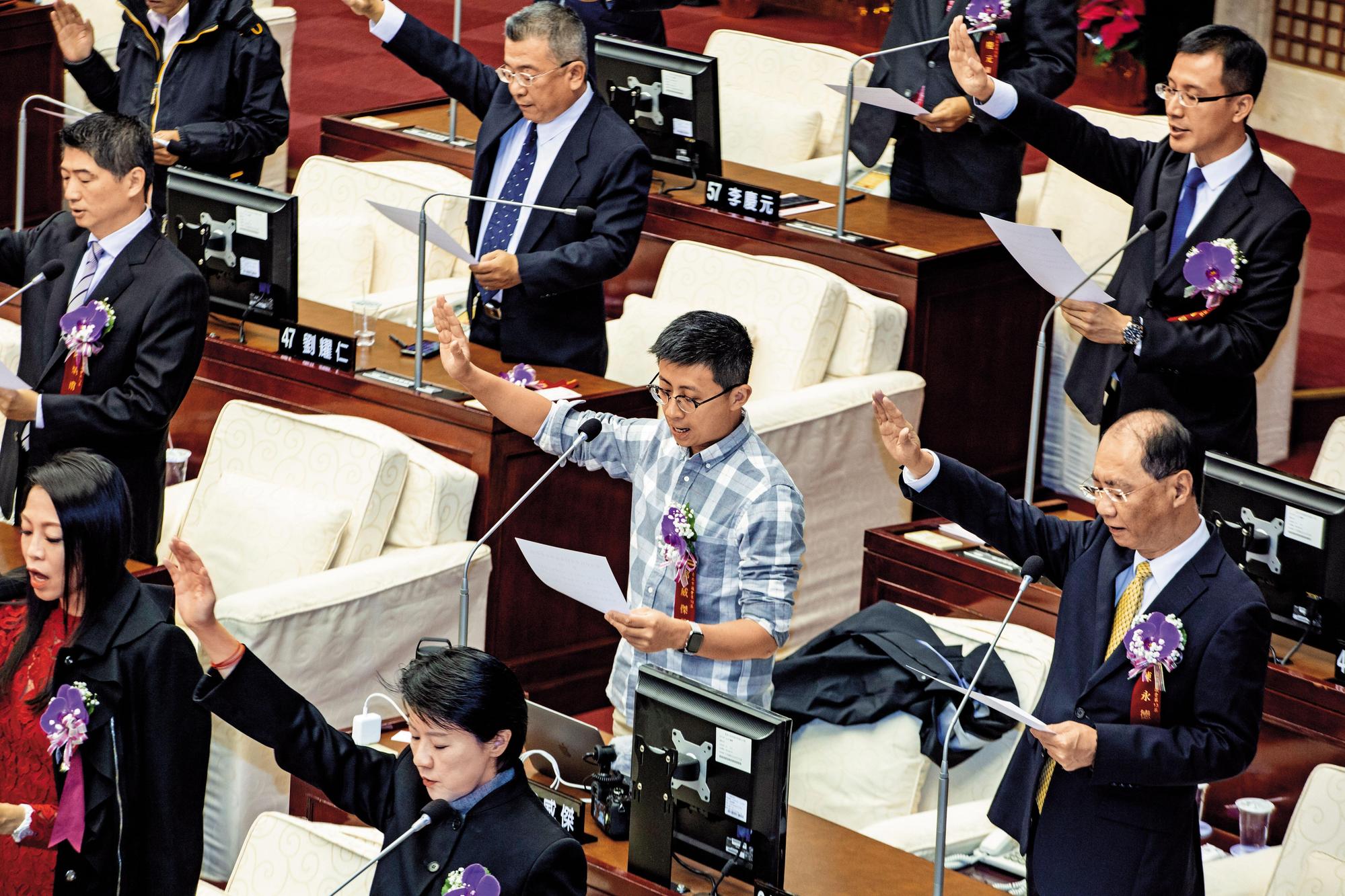 呱吉12月25日穿著襯衫卡其褲宣誓就職，形象與身旁的新科市議員大相逕庭。（王漢順攝）