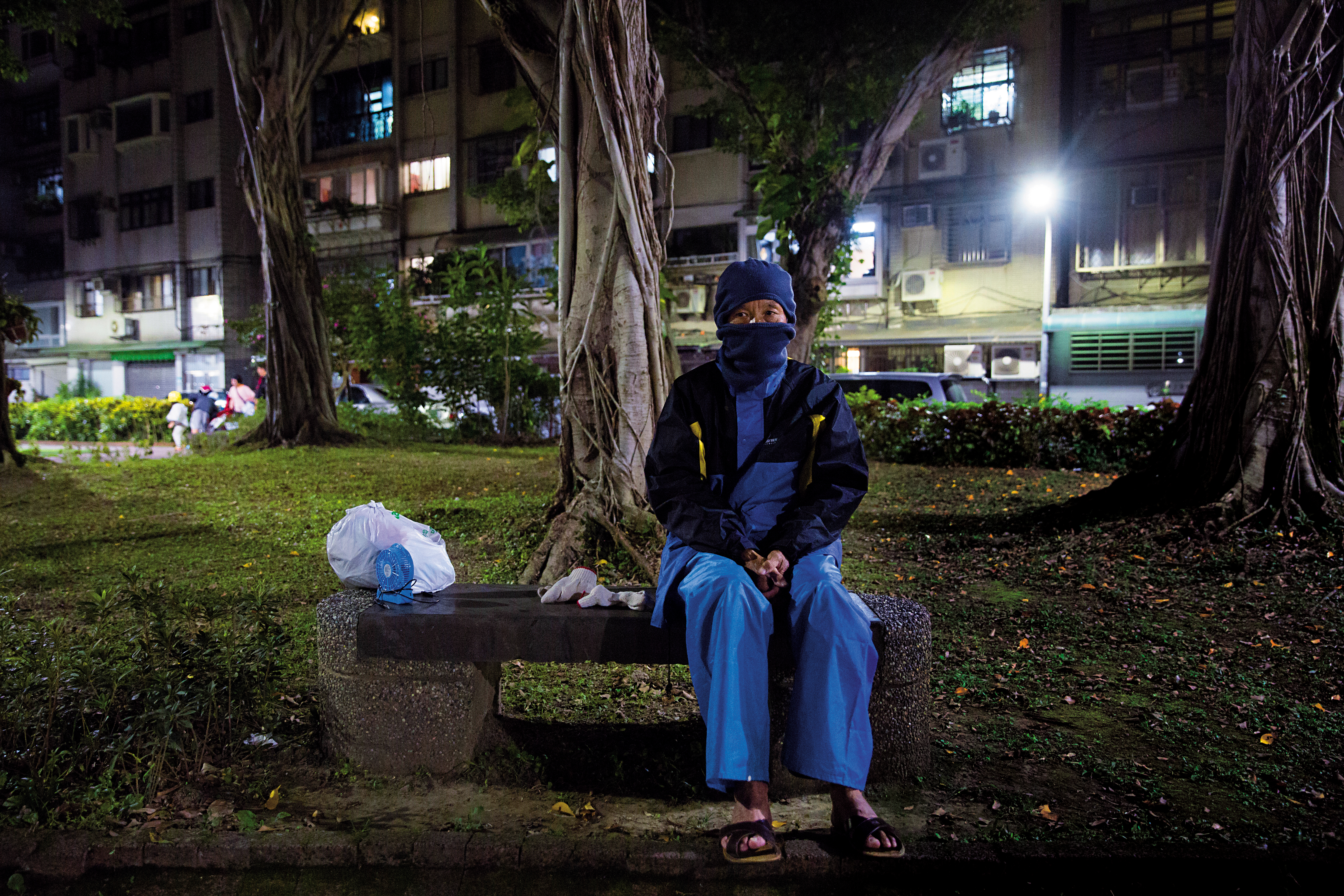 70歲老翁謝天福坐在台北101附近的公園長椅上，北上掃墓時，這裡就是他晚上的家。
