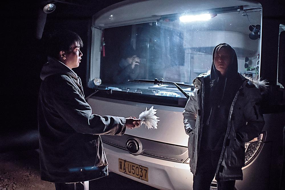 片末在巴士車燈下,演員們接踢毽子,帶出了連結與慰藉。胡波將電影拍得恢弘沉重,是這個世代的一座里程碑。(大象席地而坐宣傳團隊提供)
