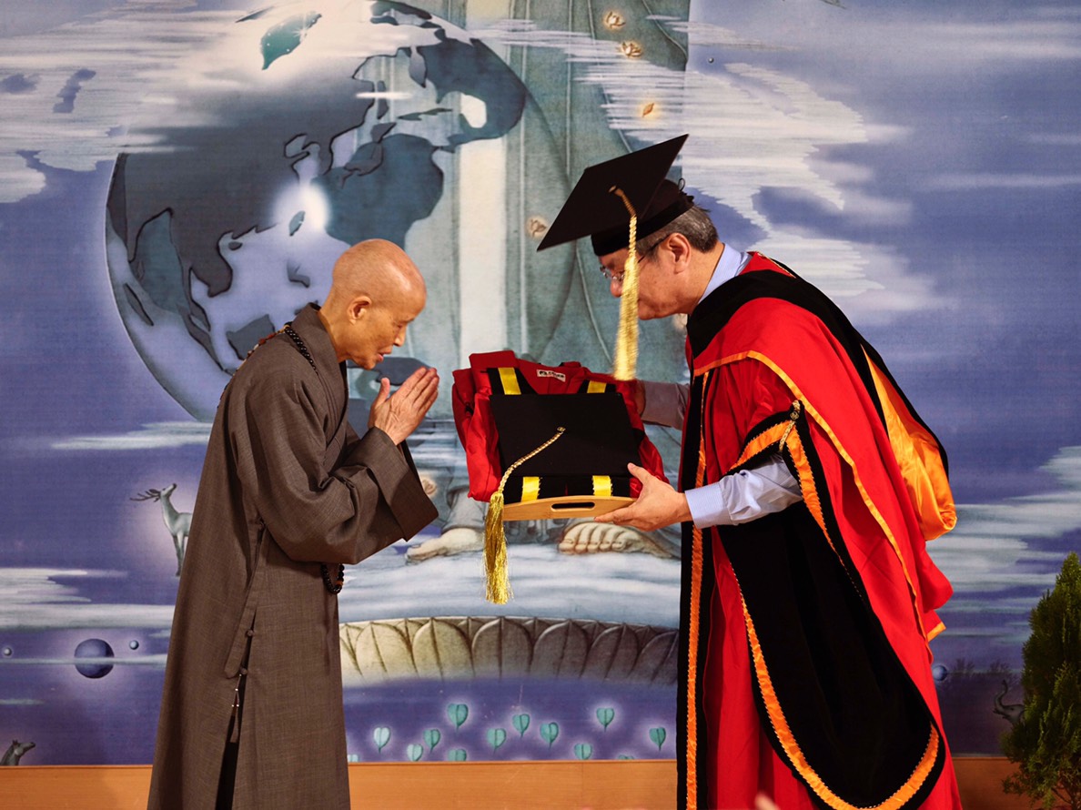 證嚴法師從中正大學校長馮展華手中接下「名譽文學博士」學位。（慈濟提供）