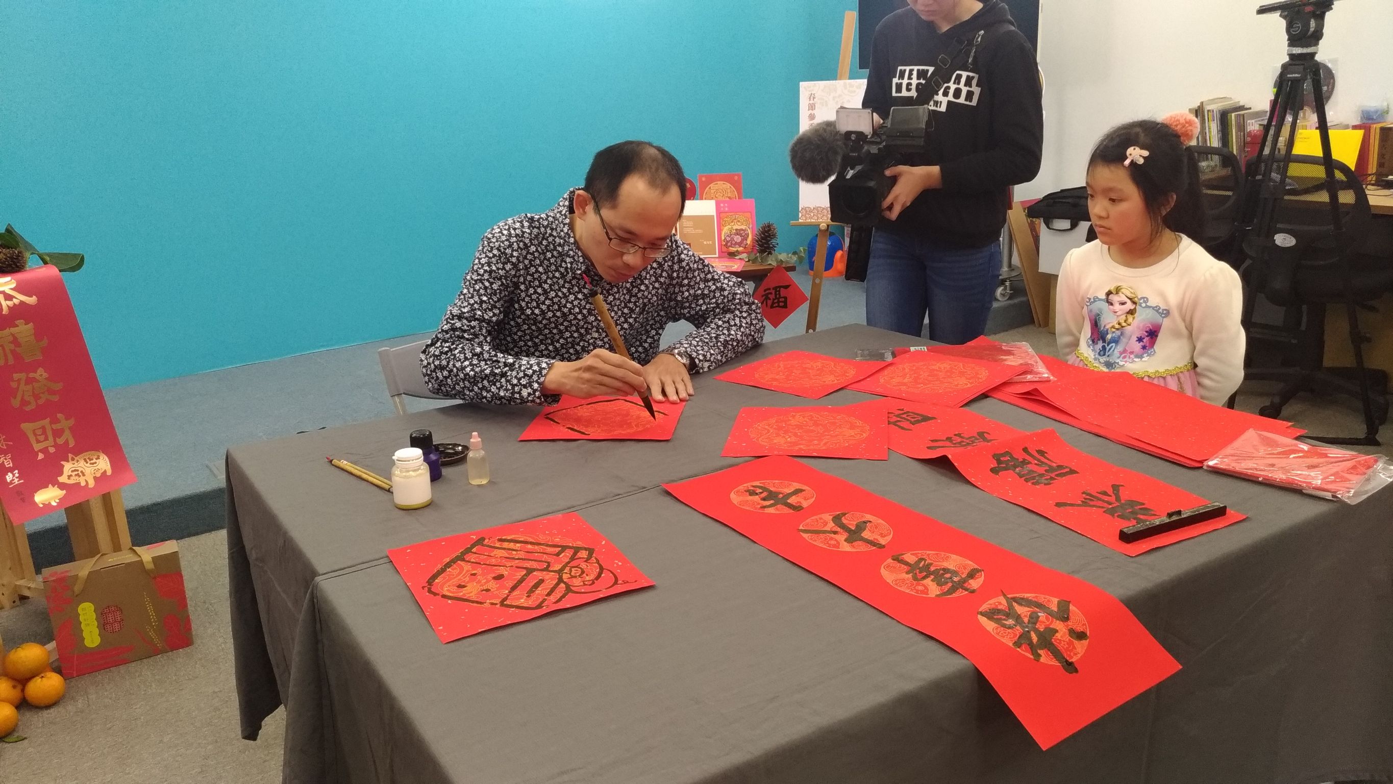 書法家蘇梓靖在記者會現場揮毫，贈送給民眾春聯沾喜氣。（讀者提供）