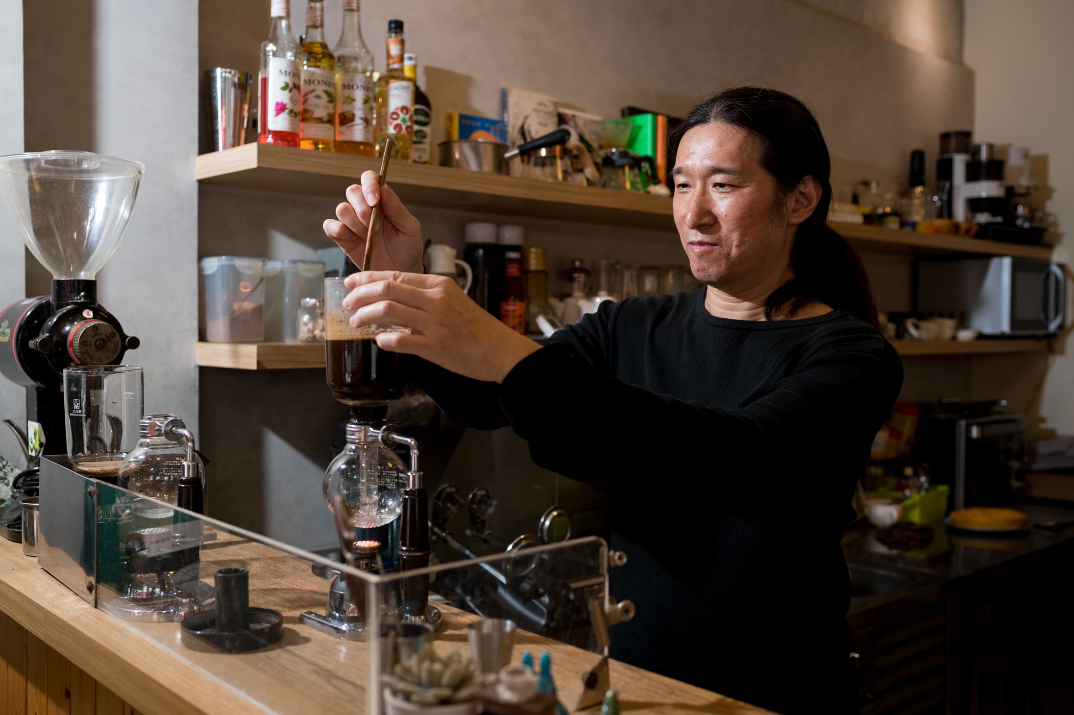 順順堂老闆Toddy專注地以虹吸式咖啡壺為客人手沖咖啡。