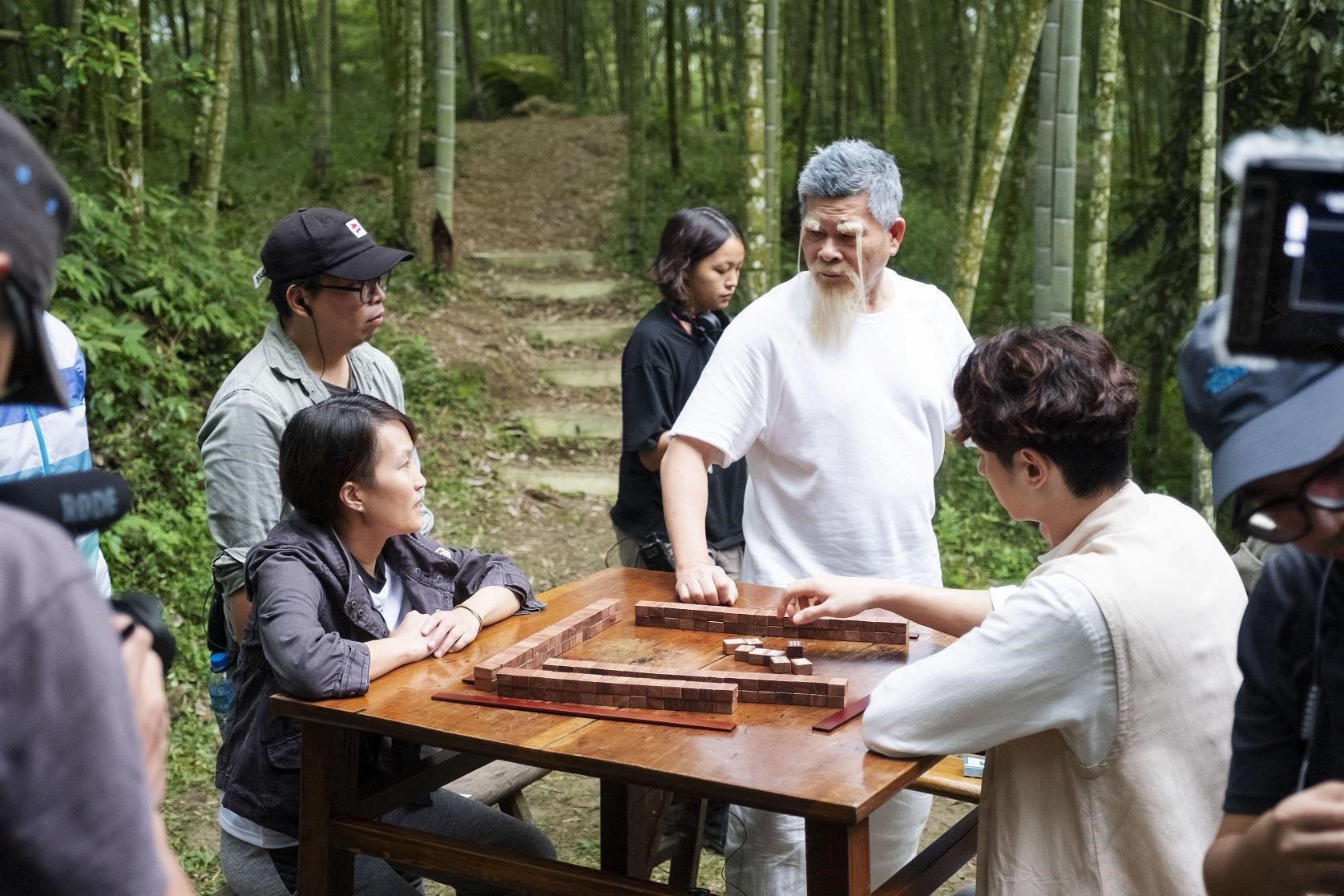 導演陳怡妤（左前）與監製兼演員澎恰恰（右三）、男主角張軒睿（右二）在「一竹居」場景討論拍攝細節。（好孩子國際娛樂提供）