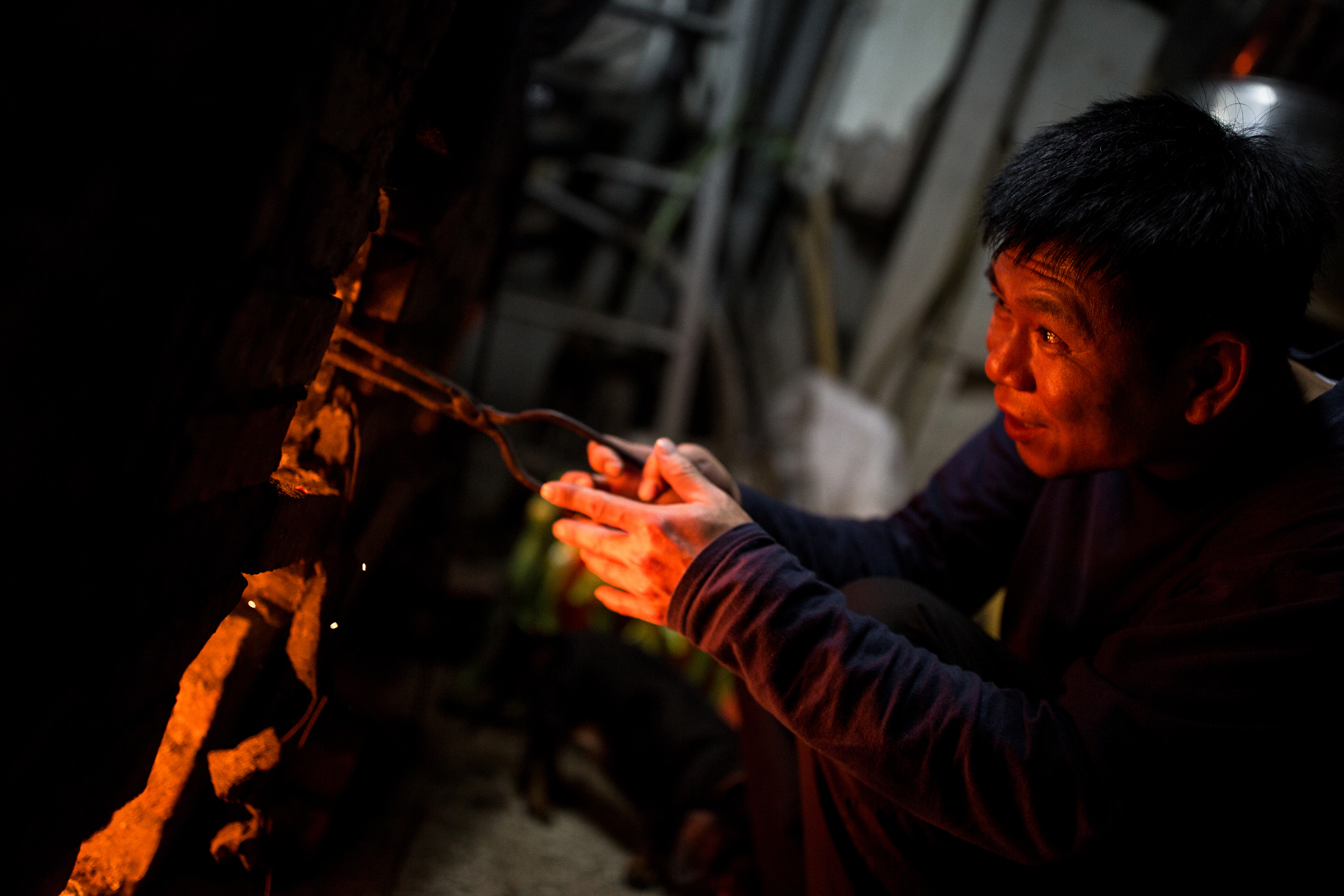 熬煮麥芽糖要注意火候，張琮翔不時要添炭或用火鉗把炭挾出，讓火變小。