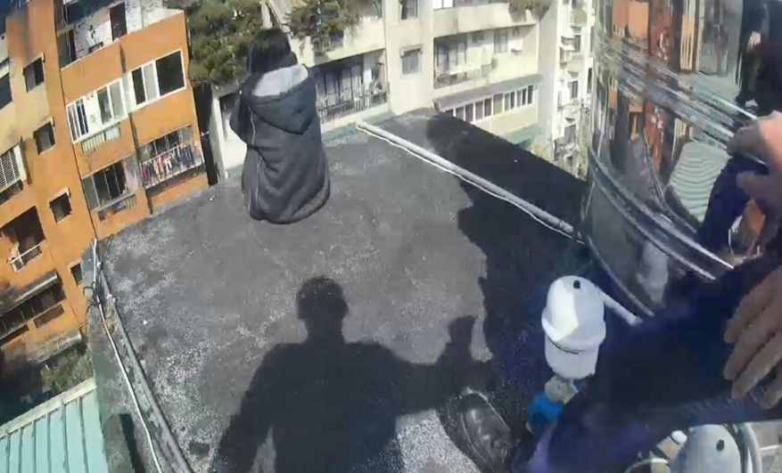 女子孤身抱膝坐在頂樓邊,隨時可能縱身墜樓。(翻攝畫面)