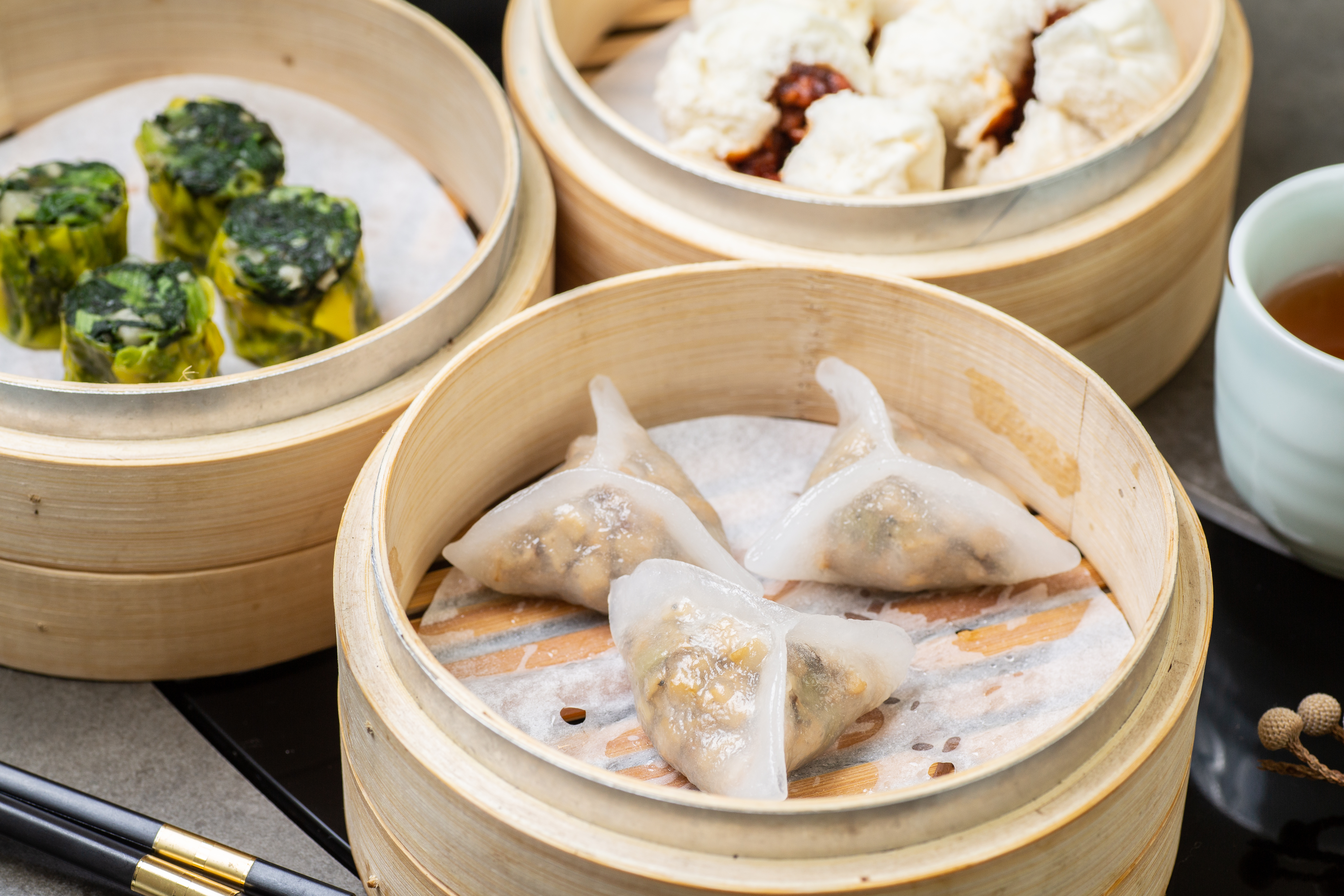 「黑松露野菌餃」（180元／份，前）皮Ｑ、松露香氣濃郁；「心齋燒賣」（140元／份，中）包進地瓜葉和青江菜。「蜜汁燒包」（120元／份，後）口味與葷的幾乎無異。