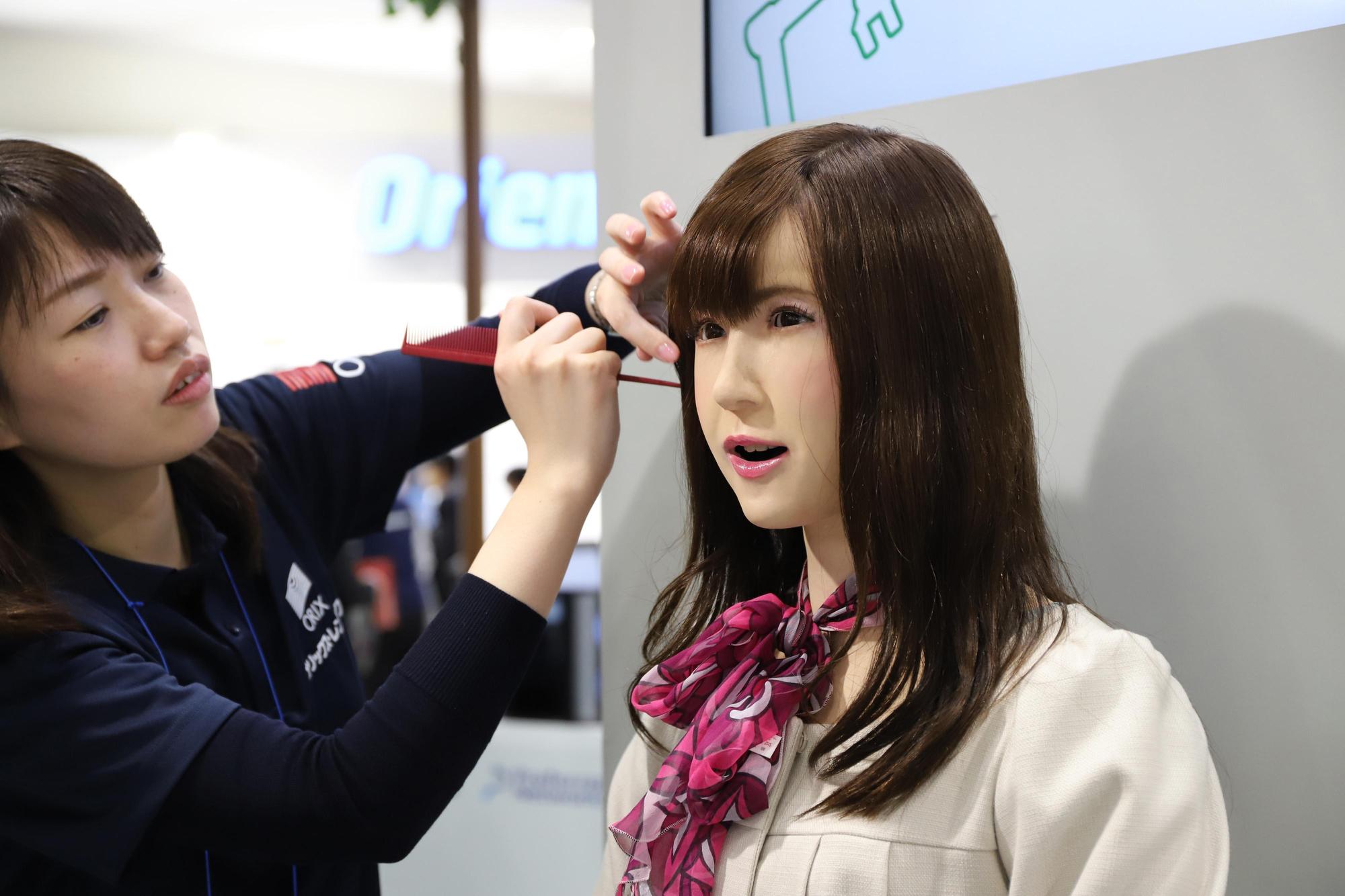 日本ORIX Rentech為機器人「小圓」整理頭上的假髮。（東方IC）