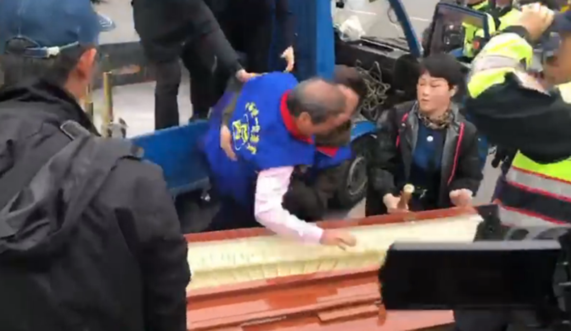 統促黨總裁張安樂昨率眾到立法院抬棺抗議，卻不小心差點摔進棺材內。（翻攝自《奉命刑事》臉書）