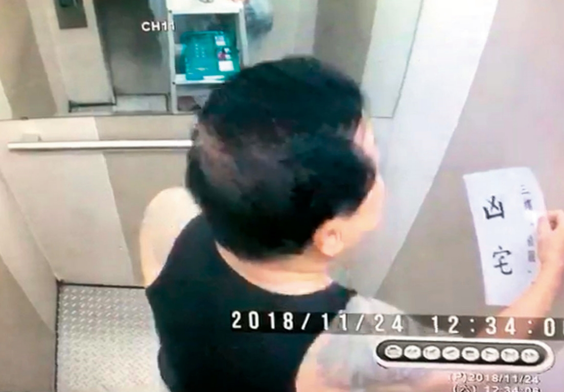 戴崇慶不滿住戶對他霸住行為提出檢舉,拿著凶宅標語在電梯間噴漆,警告意味濃厚。(讀者提供)
