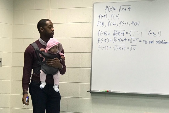 美國大學教授亞歷山大（Nathan Alexander）邊幫學生照顧女嬰，一邊寫下數學公式授課。（翻攝自推特）
