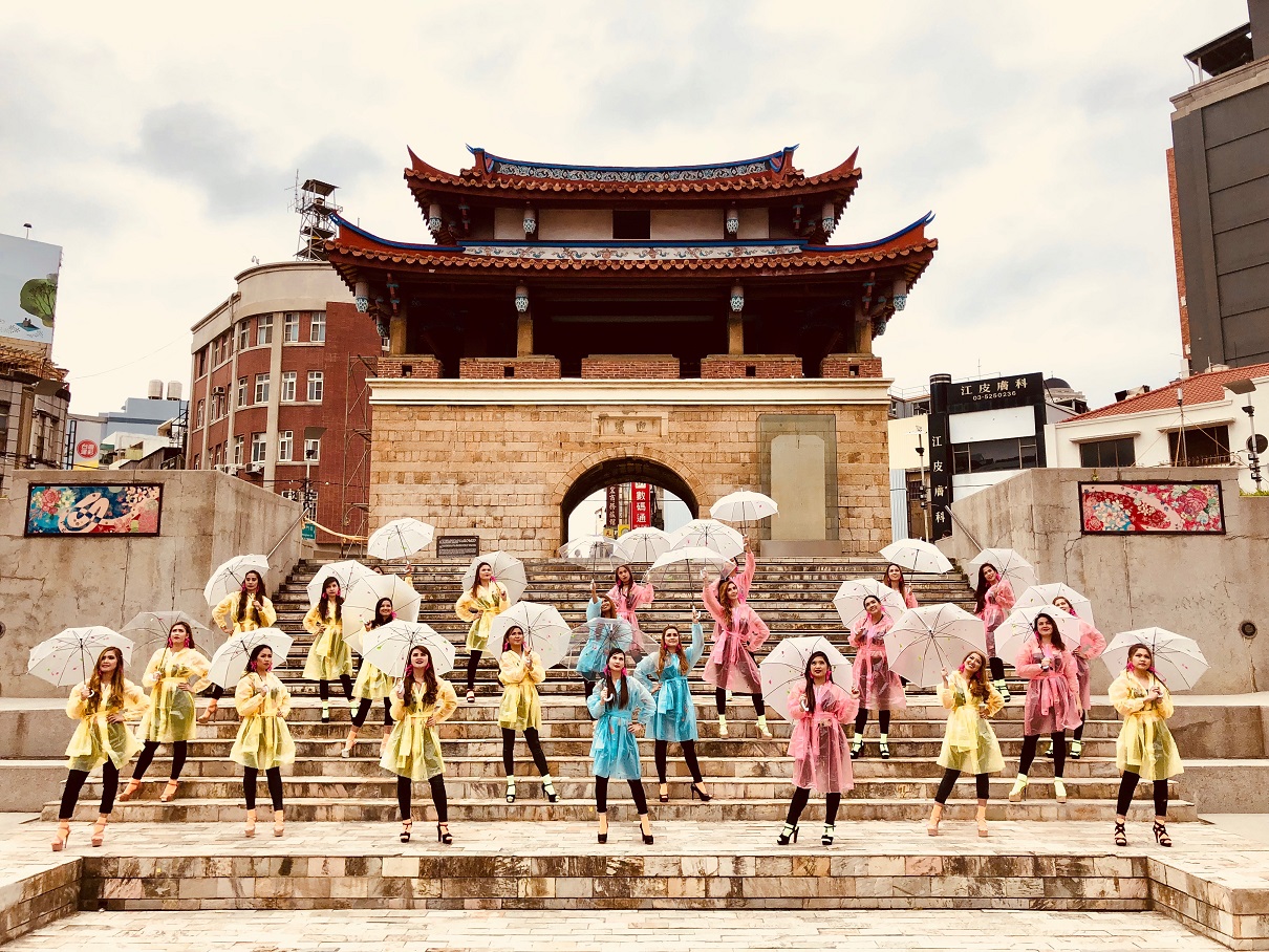 一群菲律賓移工站在城門前，拍出定裝照。