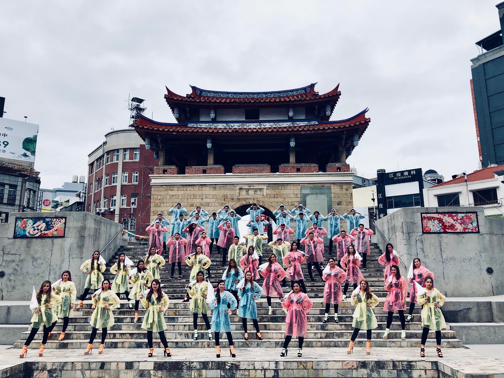 男女共20人的移工，女生拿傘，各自不同顏色的雨衣，展現菲律賓的天氣。