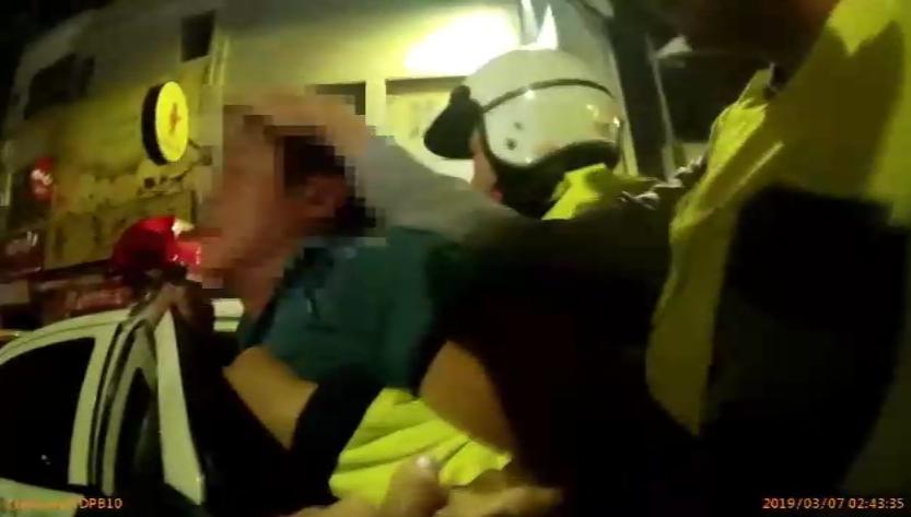 喝得醉醺醺的黃男過馬路遭小黃擦撞,一氣之下痛毆運將,警方將他帶上警車。(警方提供)