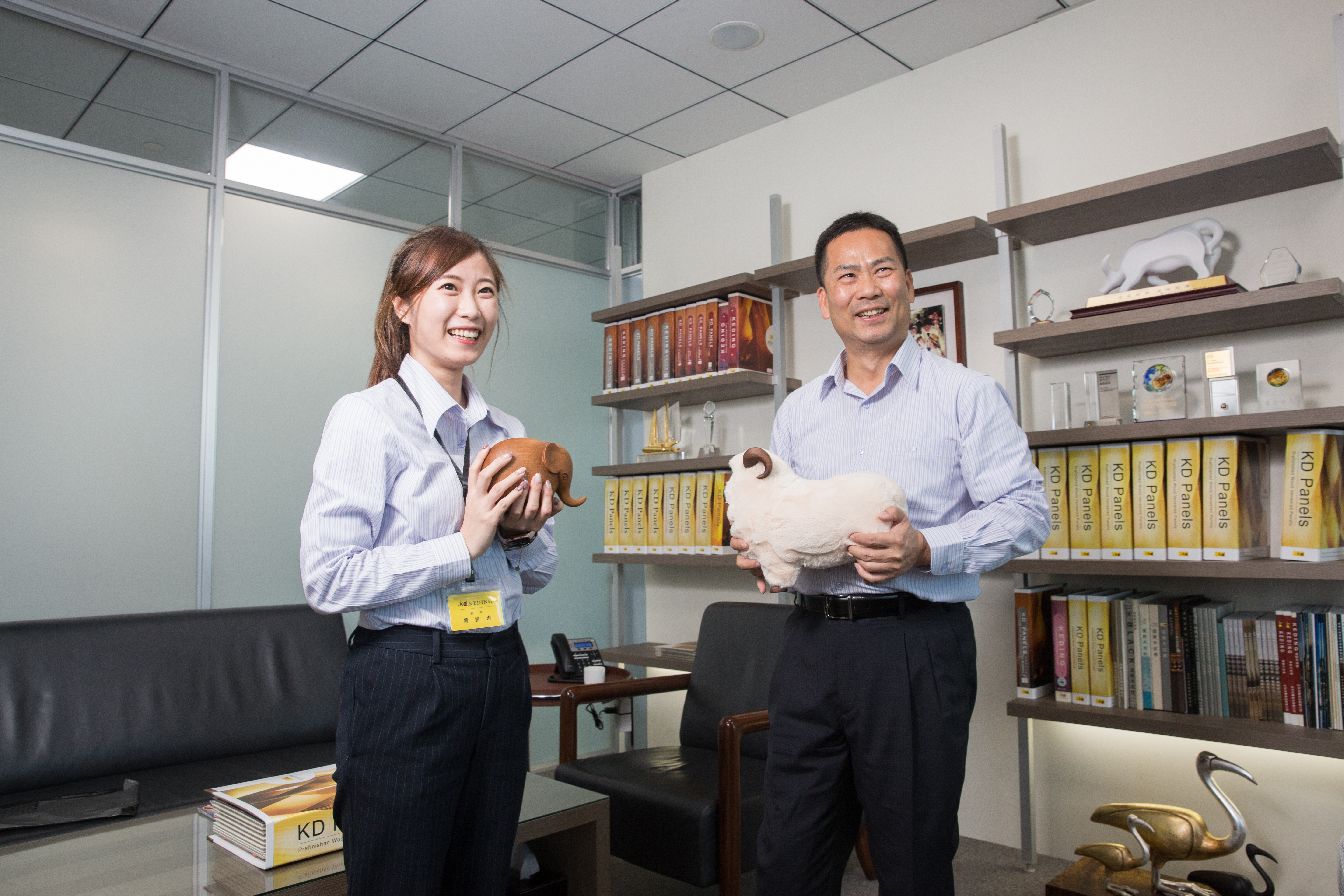 曹憲章（右）與去年進入科定擔任特助的女兒曹雅琳（左），手上分別拿著大象及綿羊的家飾品。