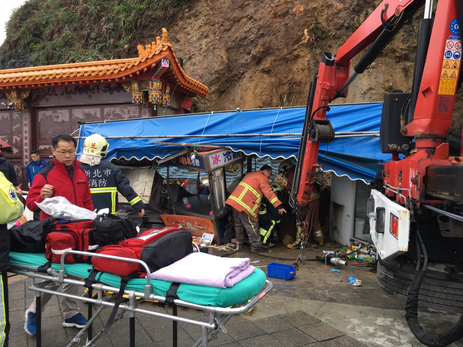 十八王公廟後方土石滑落，造成前方賣燒肉粽的攤商夫妻不慎遭壓傷。（翻攝畫面）