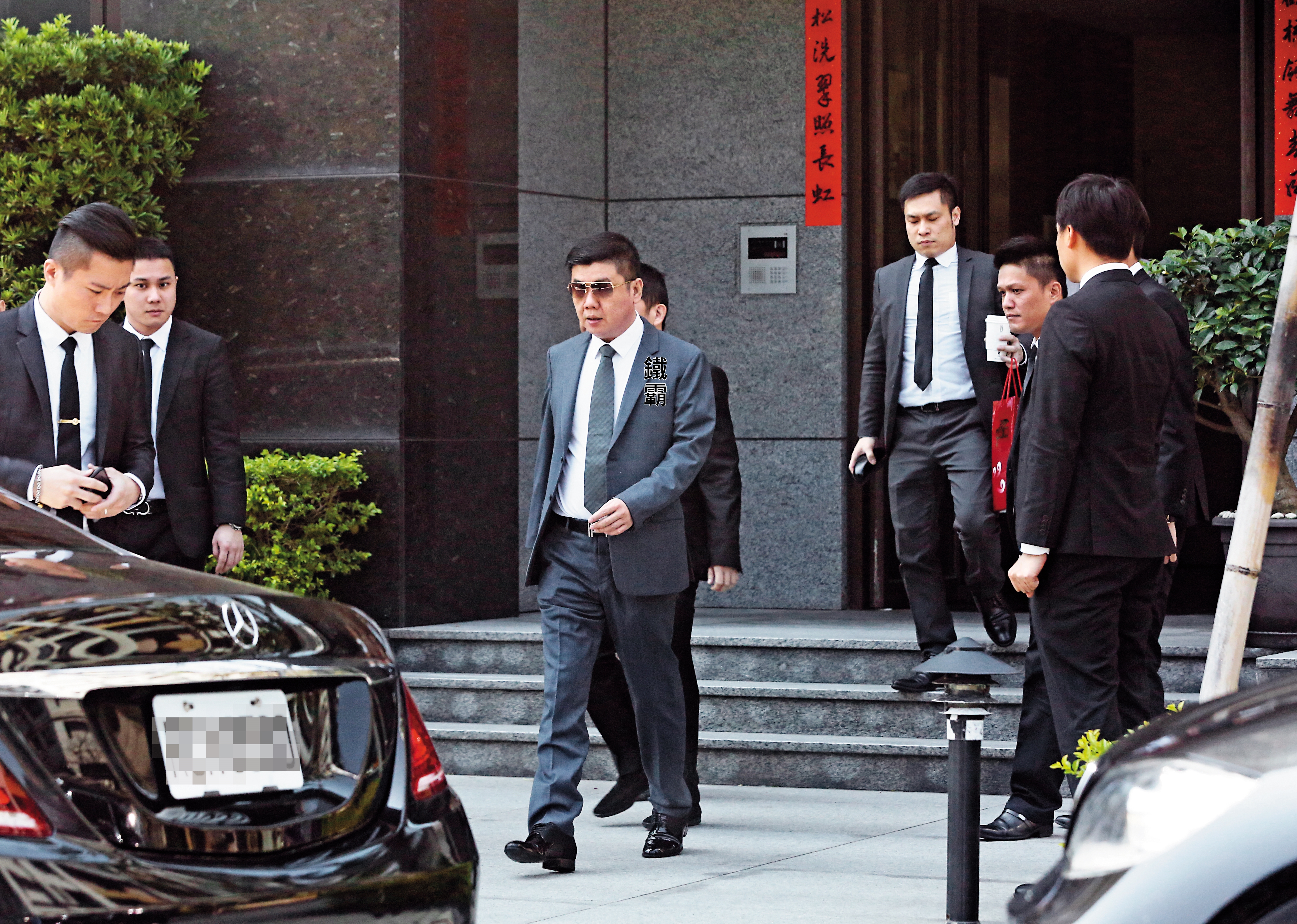 3/12 10:40 天道盟新盟主鐵霸排場不小,出入都有黑衣西裝男簇擁、保護。