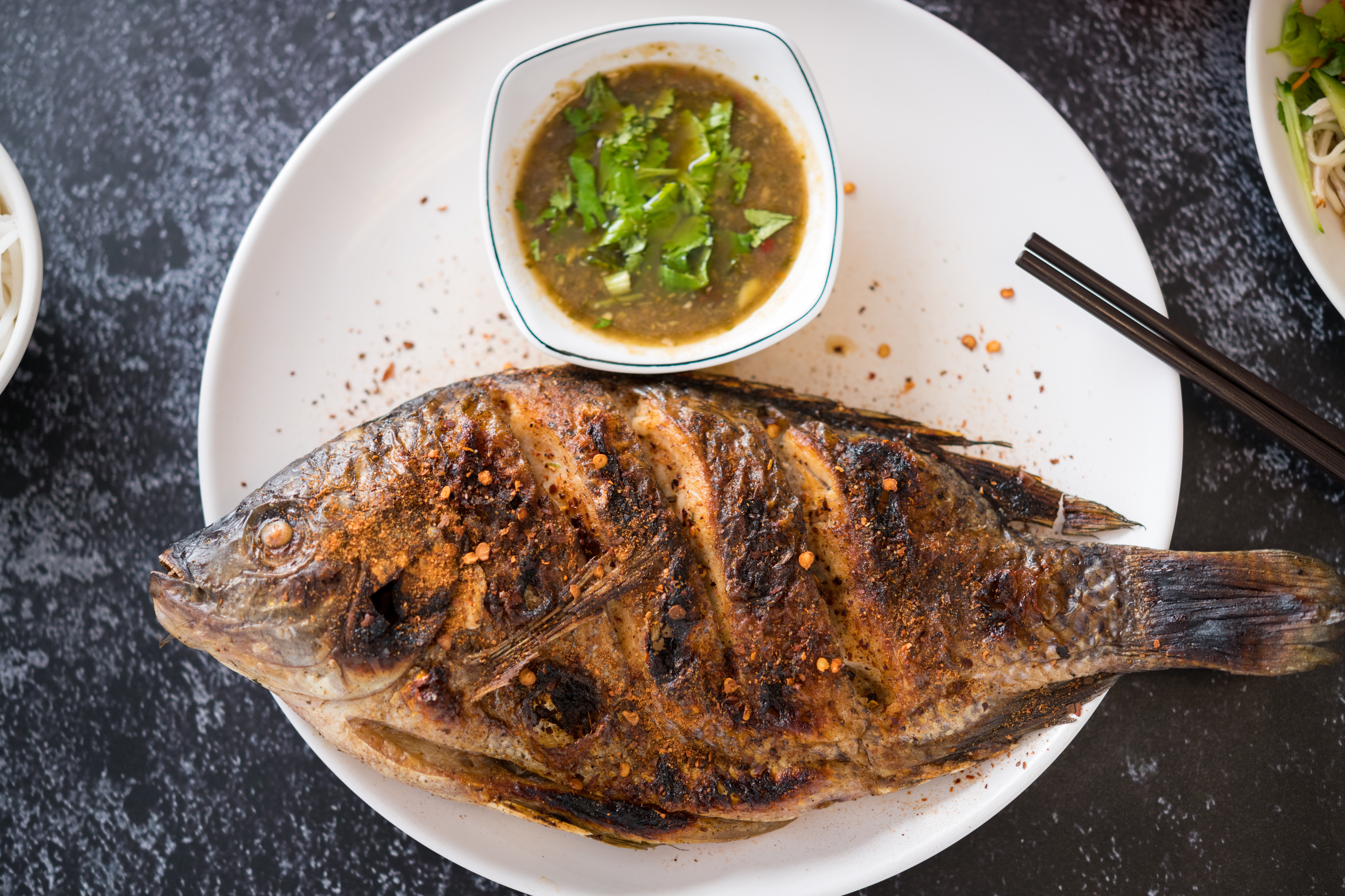 「烤魚」的魚皮酥香脆口，肉質嫩甜不柴，香料味滲透其中，蘸著醬吃，酸甜辛香。（150元／份）